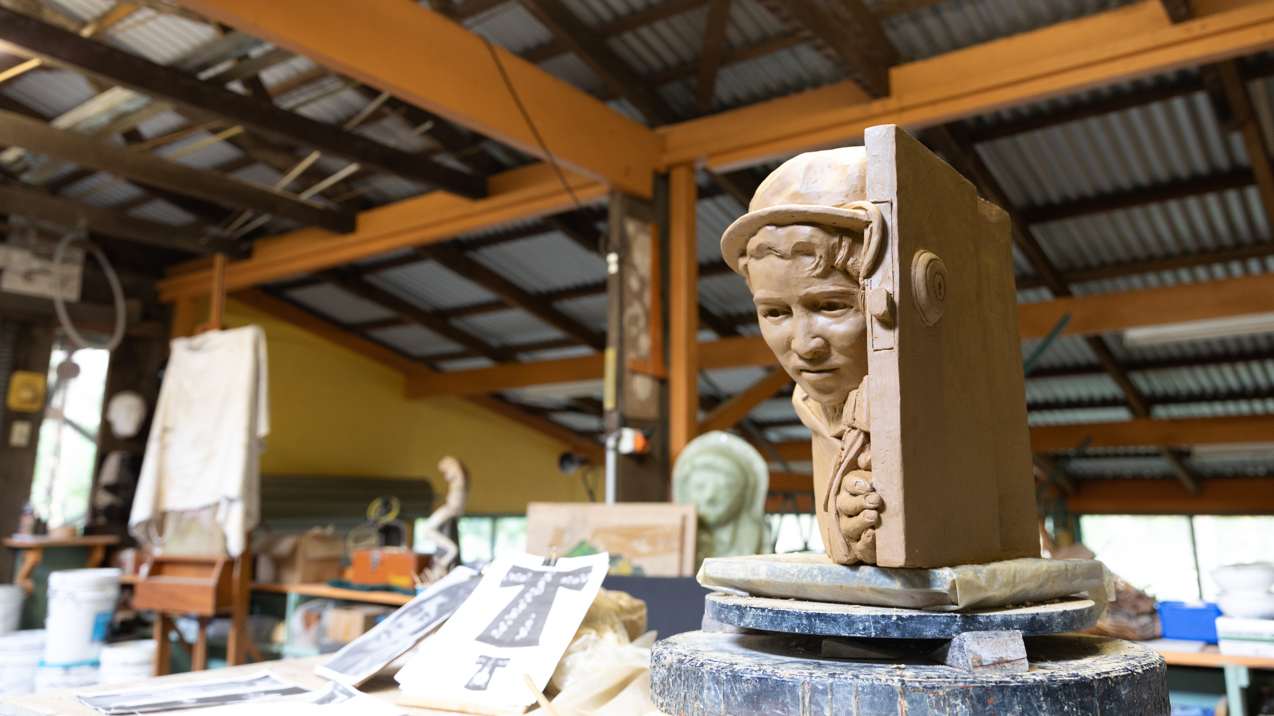 The maquette of Margaret Valadian sits on Dr Hinwood's work bench, with tools and images the Officer of the Order of Australia insignia laying beside it.