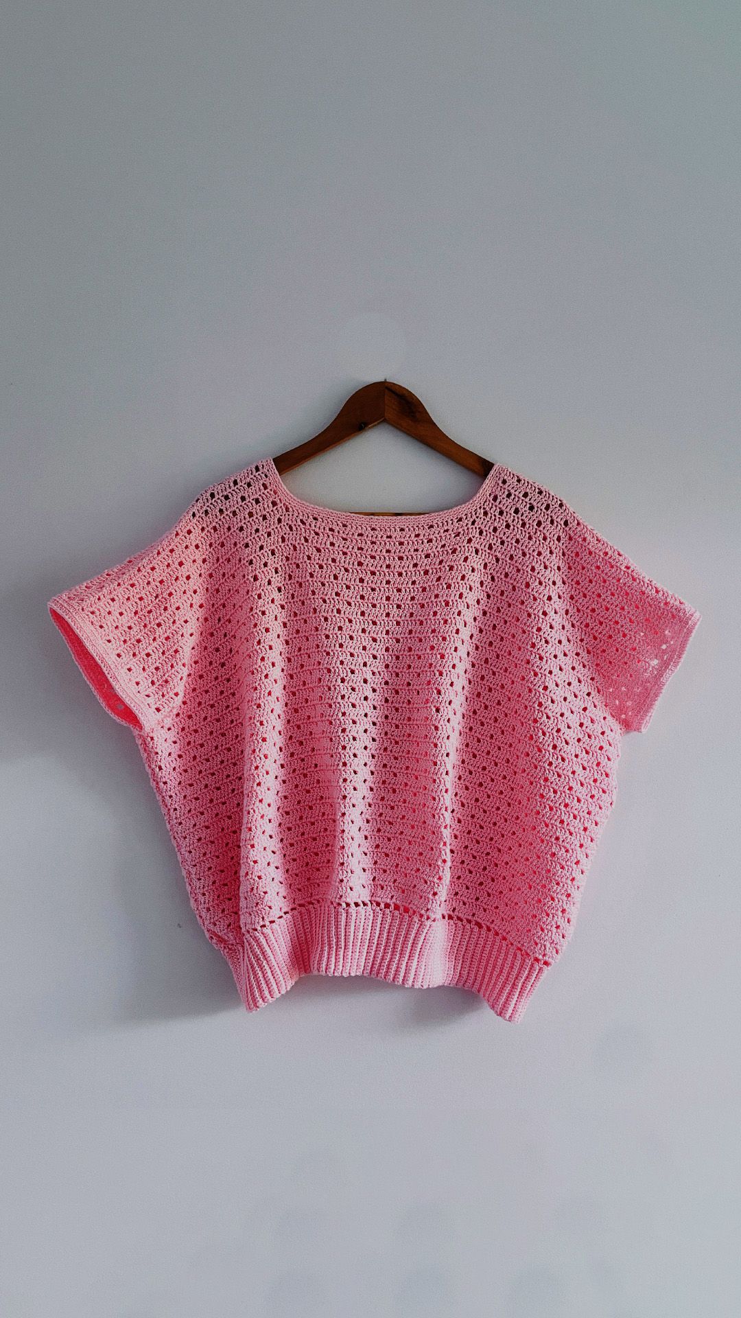 A pink knitted shirt on a hanger