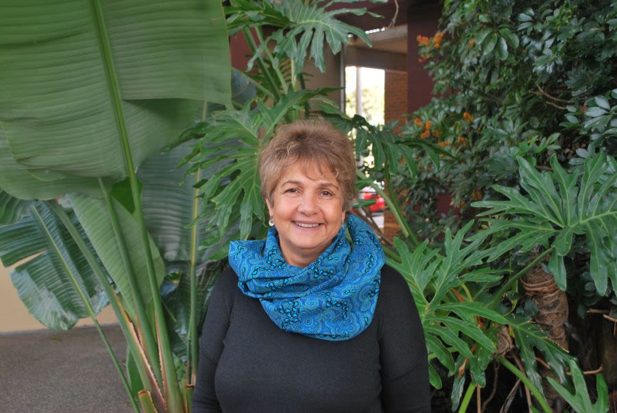 Professor Gail Garvey smiling in front of a garden of plants