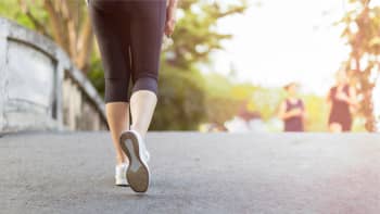A woman walking across a bridge for exercise in the early morning light.