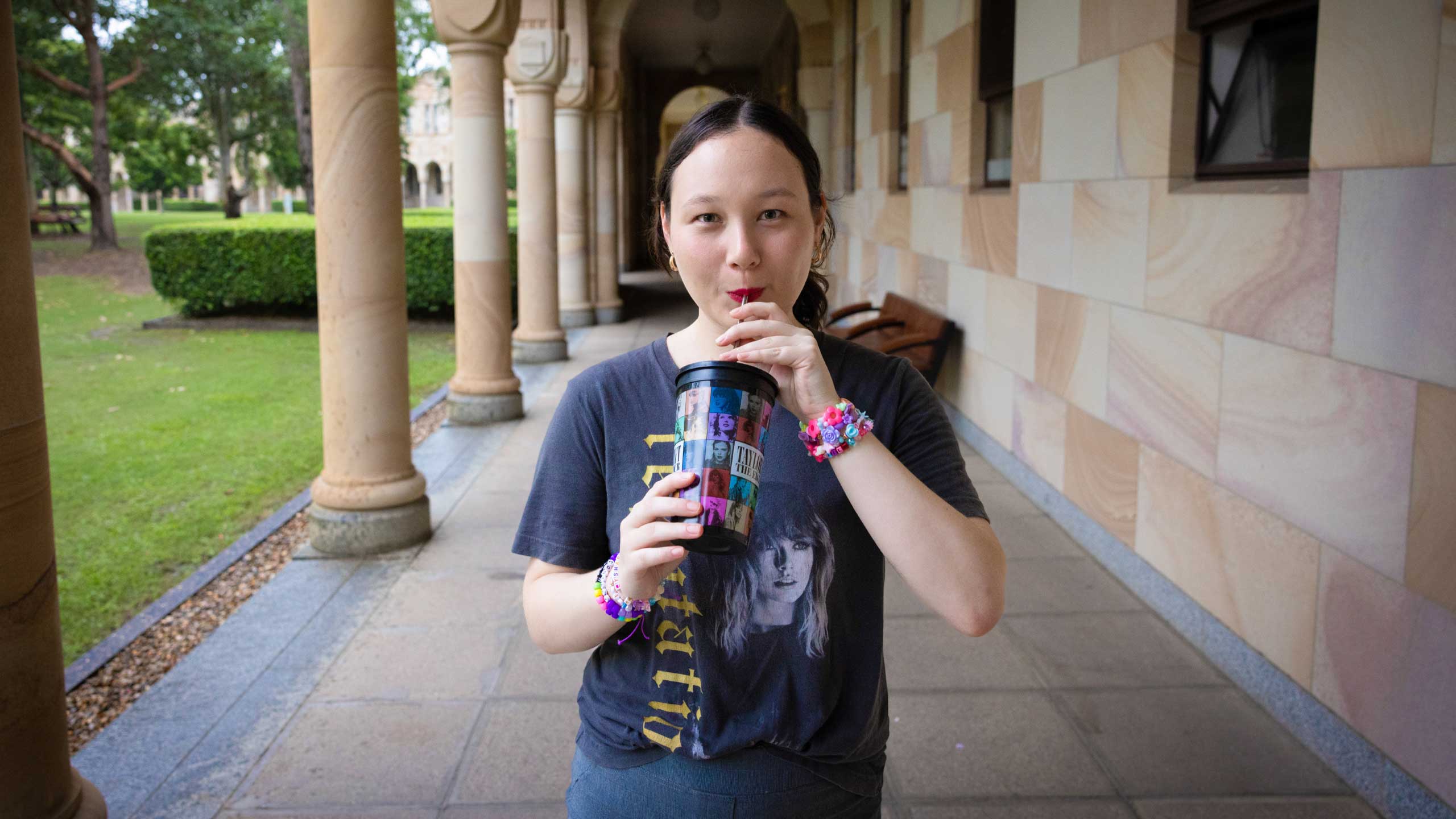 Emma sipping out of a Taylor Swift drink bottle, while standing in UQ's Great Court.