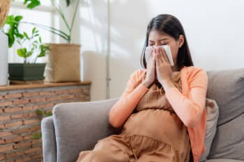 Pregnant woman blowing nose with tissue