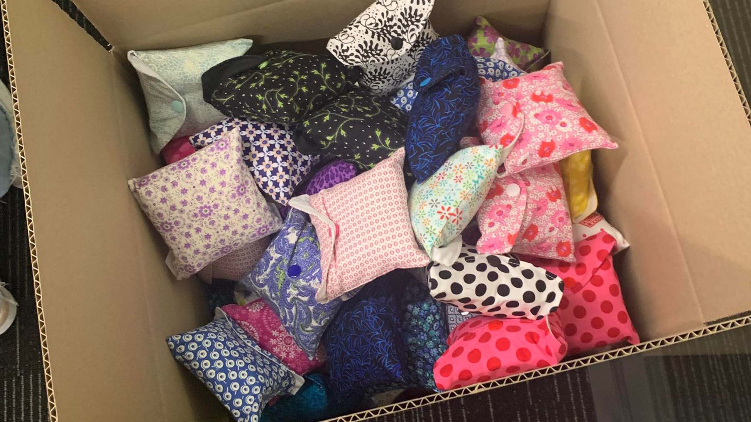 A box with small cloth bundles in assorted colours which hold menstrual hygiene products