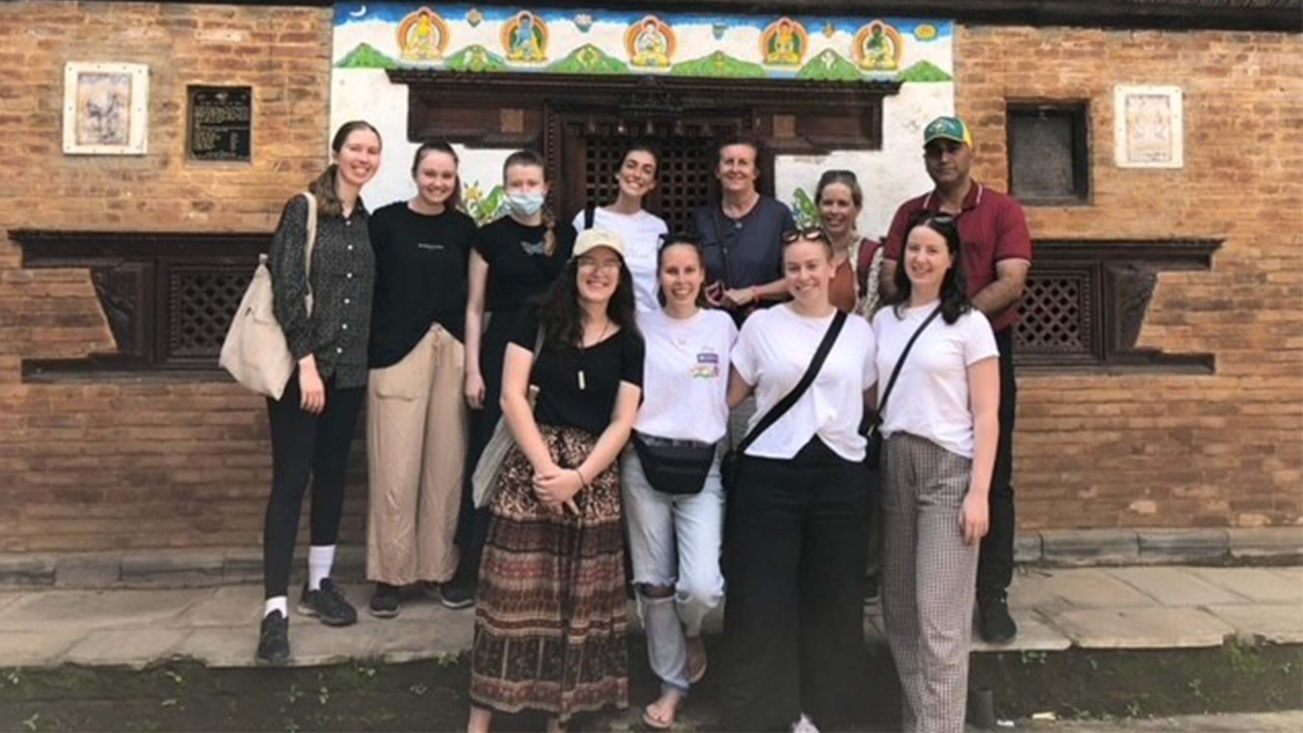 UQ students stand in two rows for a group photo in casual clothing. They are with their facilitator Alison Bourke and a local man.