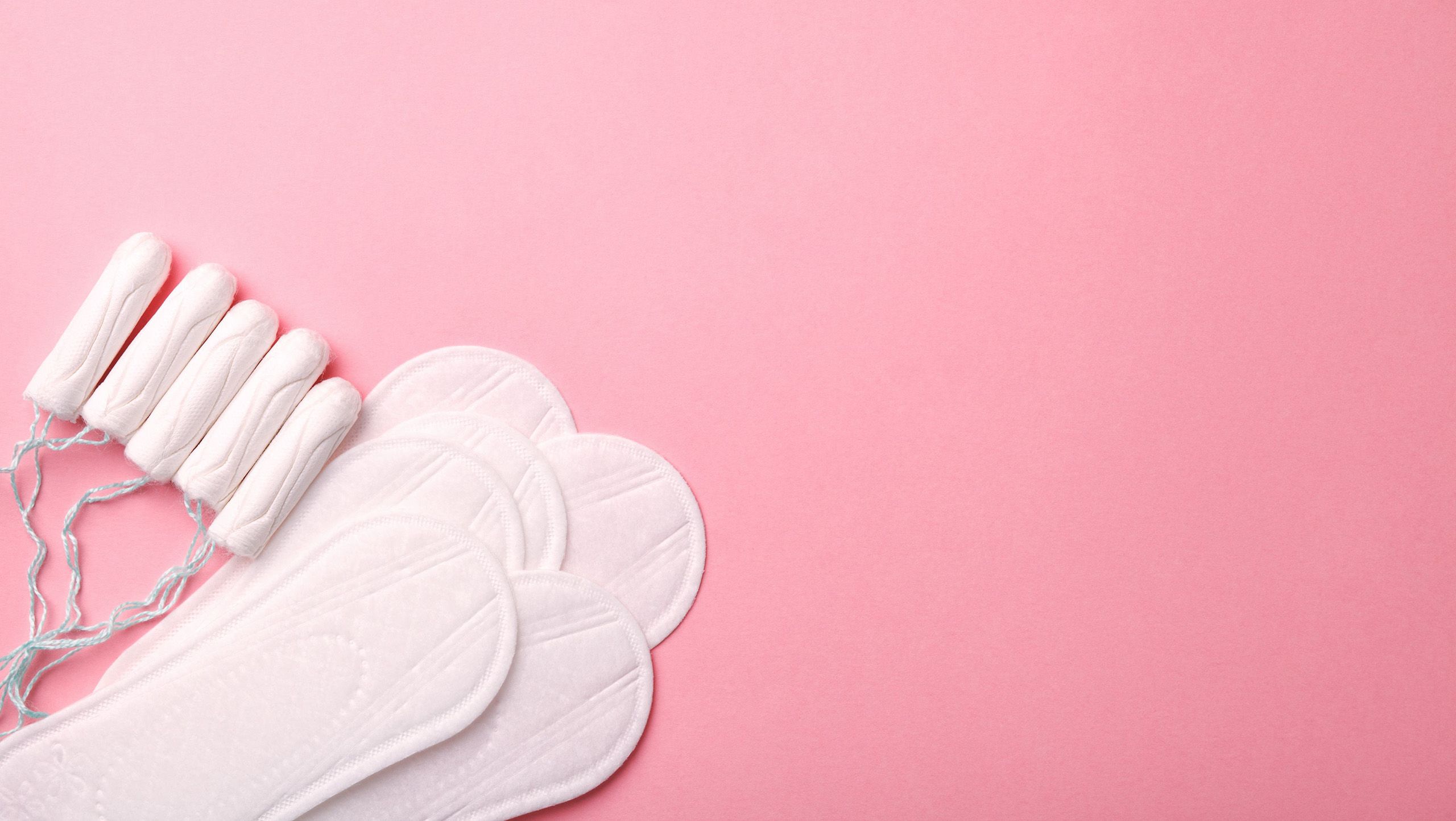 Tampons and pads sitting against a pink background