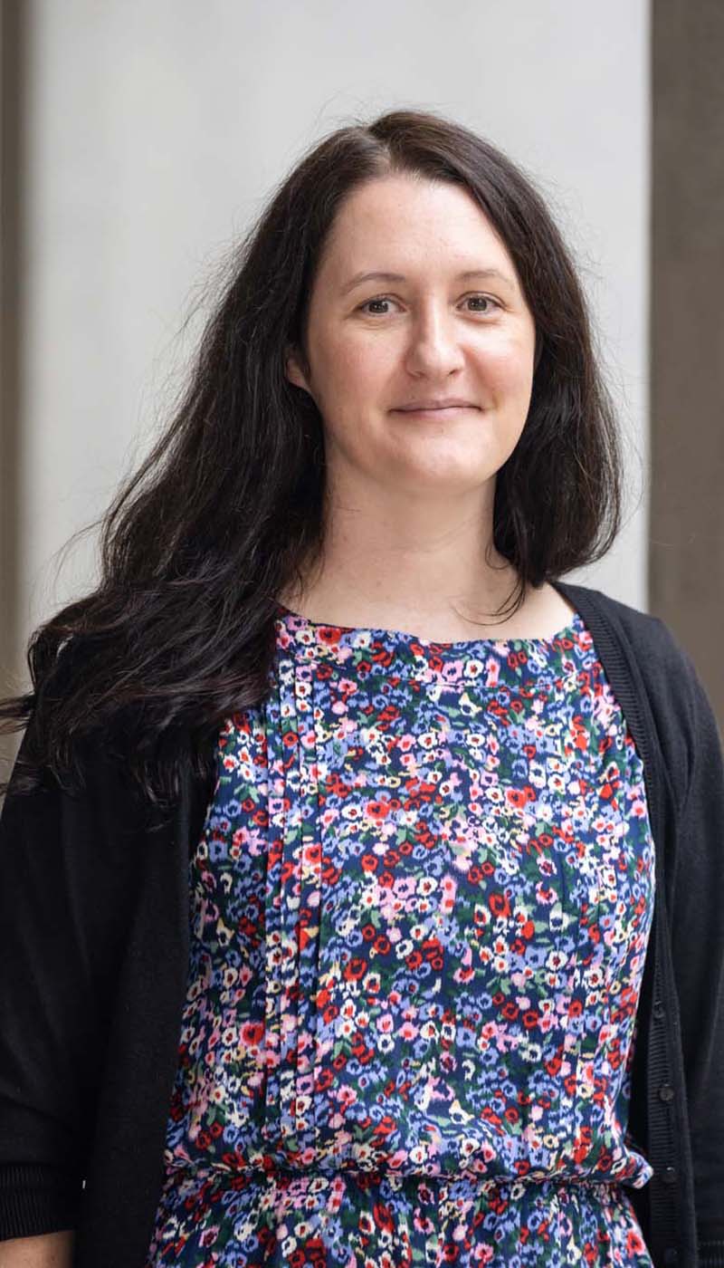 Women with long dark brown hair and brown eyes in a floral dress and black cardigan