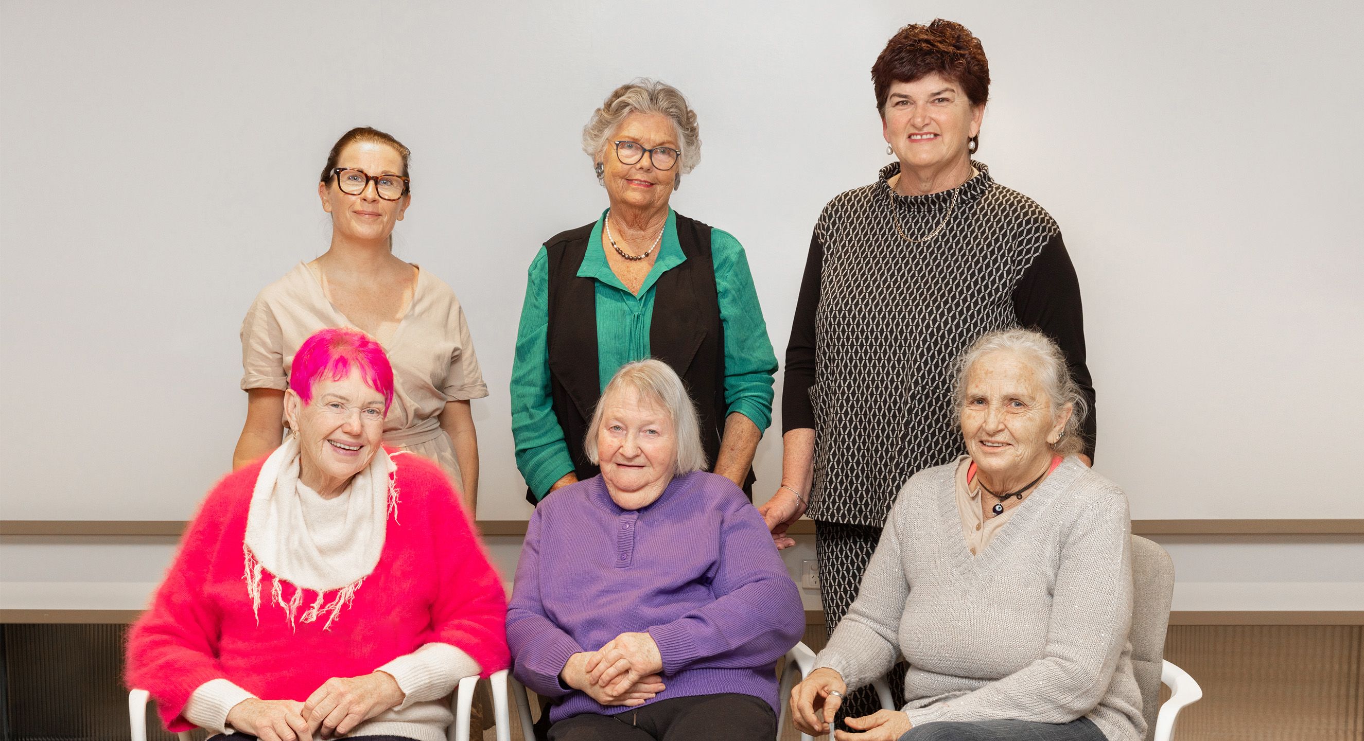 Group of six women in two rows smiling at the camera for a group photo.