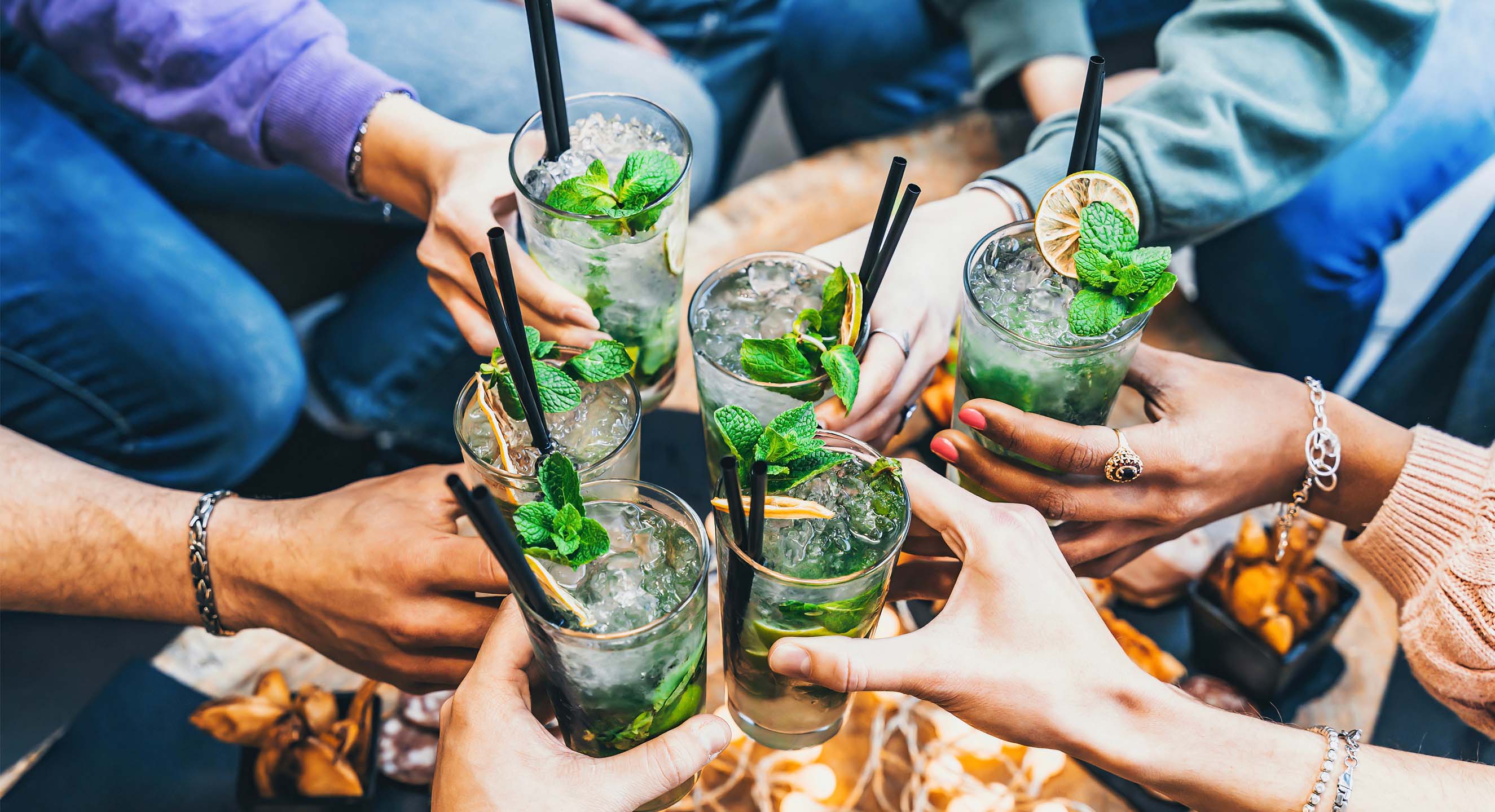 Five people holding cocktails together in a 'cheers' motion