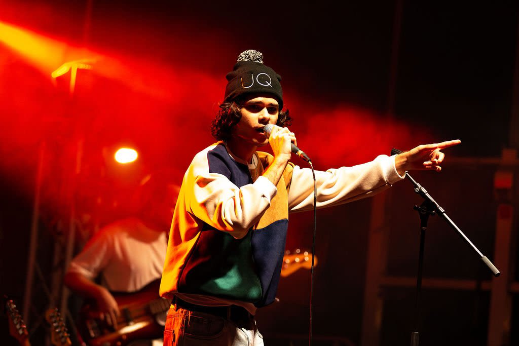 Budjerah, an Indigenous musician, holding a microphone while performing on a stage