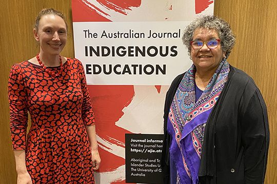 Dr Katelyn Barney and Professor Tracey Bunda in front of a sign reading 'The Australian Journal of Indigenous Education'
