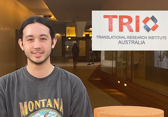 Callan Rudd-McMahon smiling in front of a Translational Research Institute Australia sign