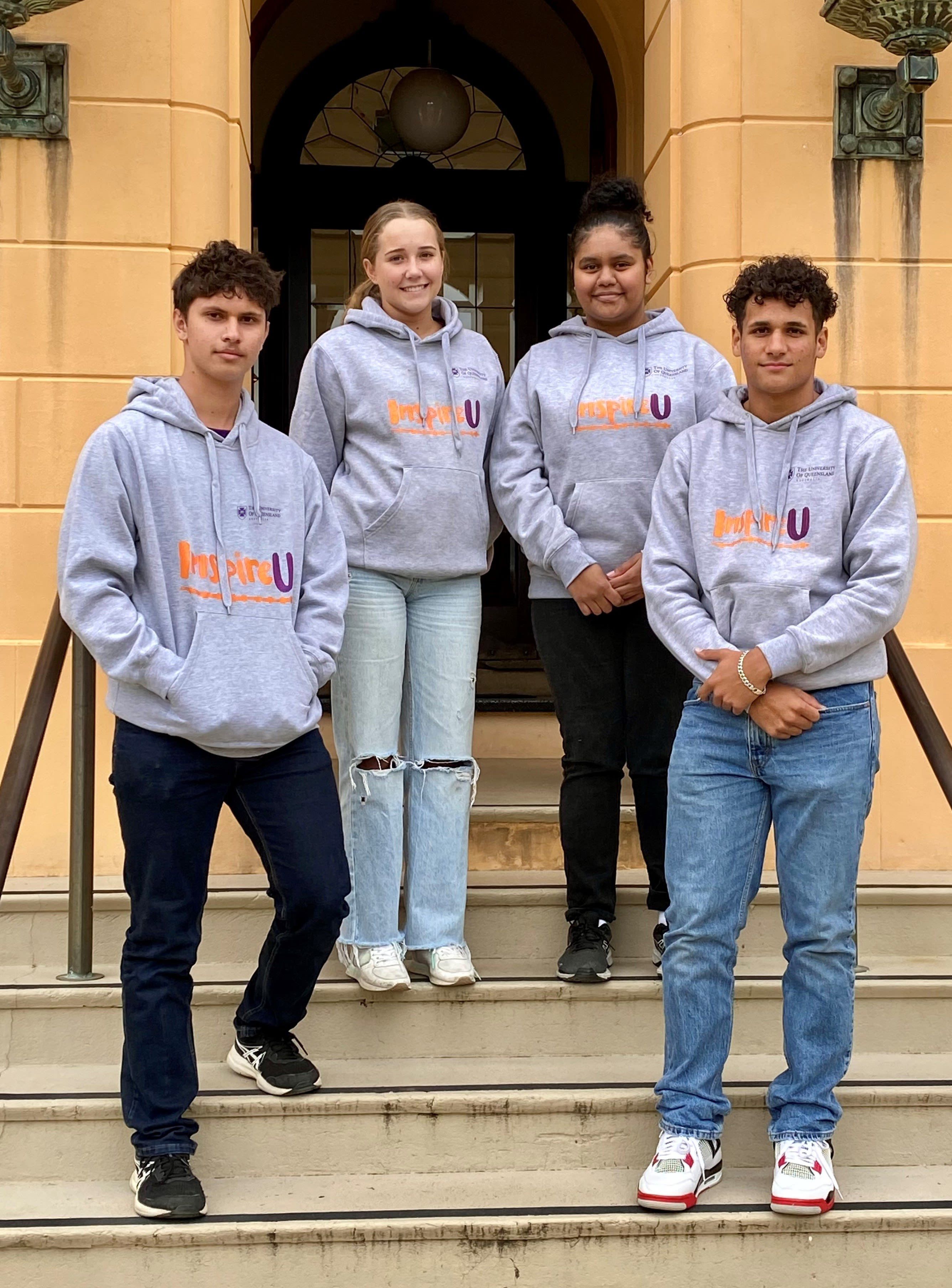 Four high school students in matching grey hoodies with the words 'InspireU' printed on the front.
