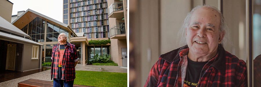 Kev Carmody standing with his hands behind his back and smiling in front of a tall residential building and a small house with a glass wall. In a second image, Kev is smiling while leaning against a wall.