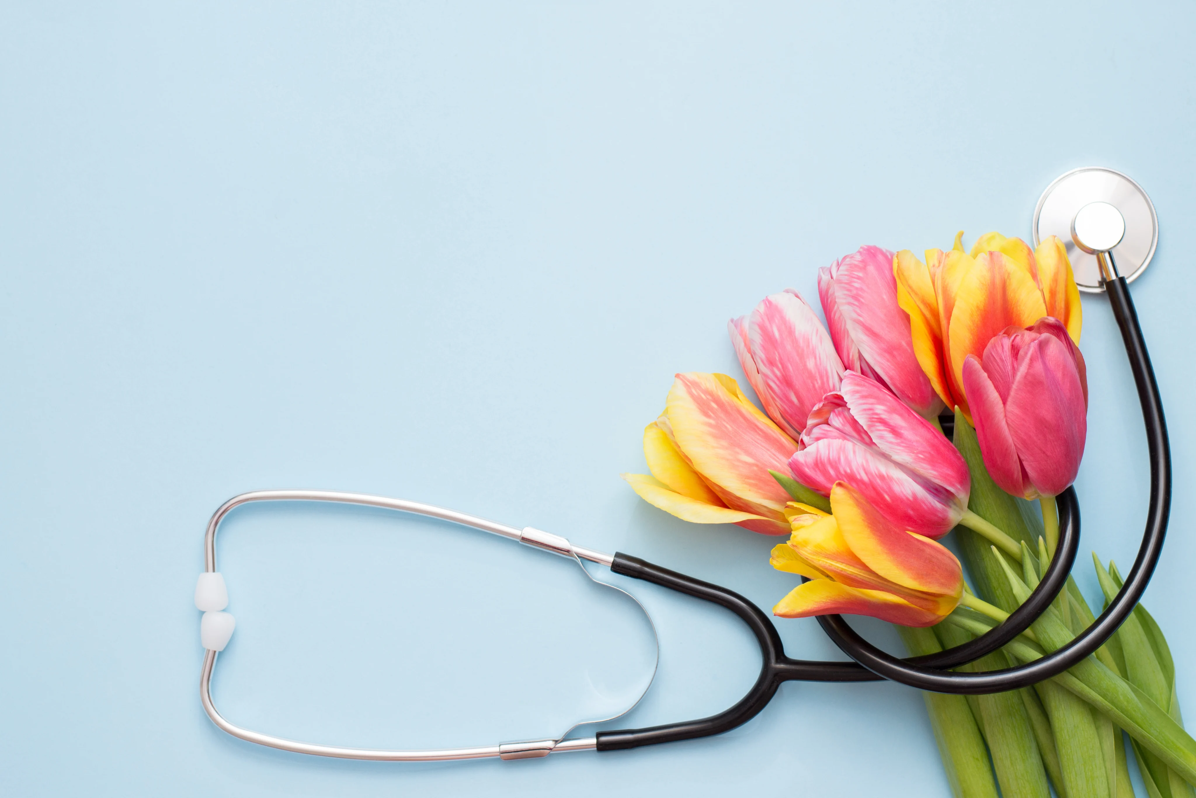 Stethoscope wrapped around pink and yellow flowers