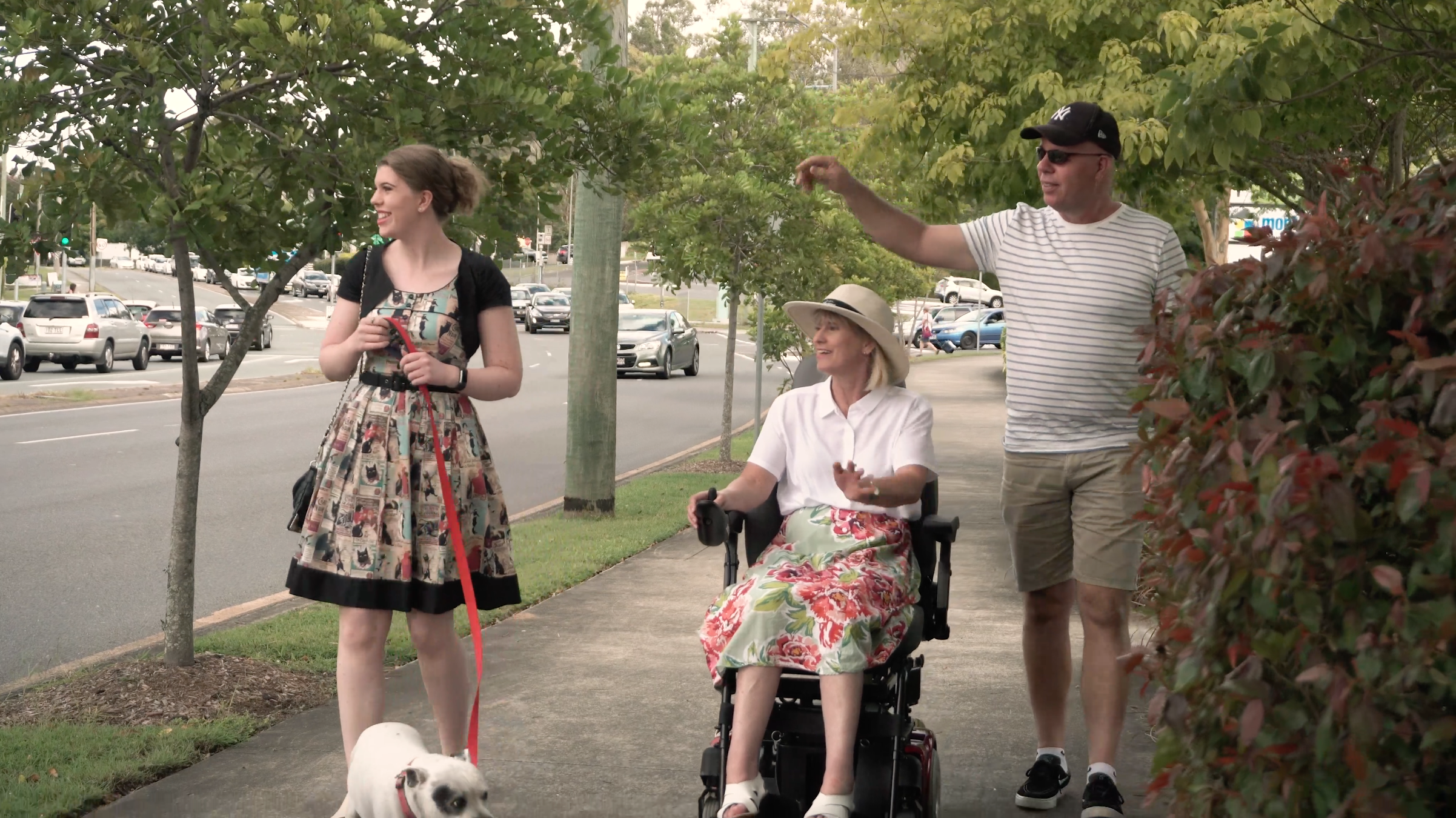 woman and man walk next to woman in wheelchair.