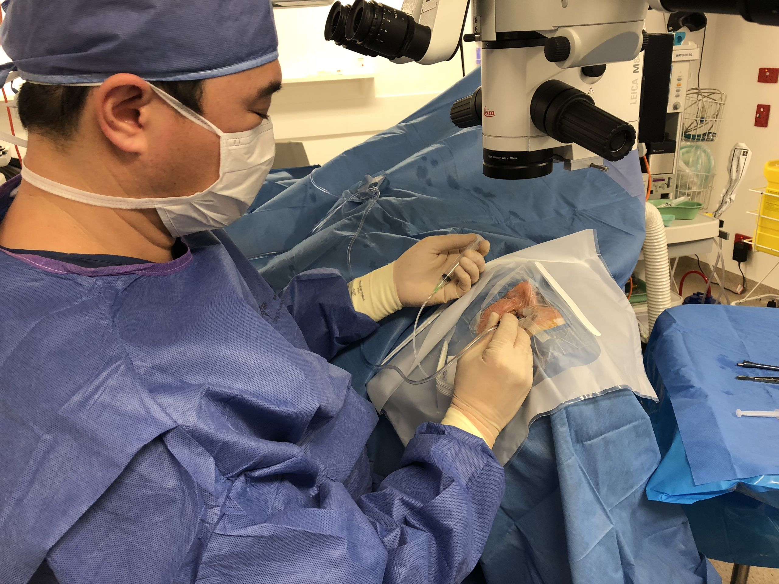 man operates on open eye, surgery equipment is around him