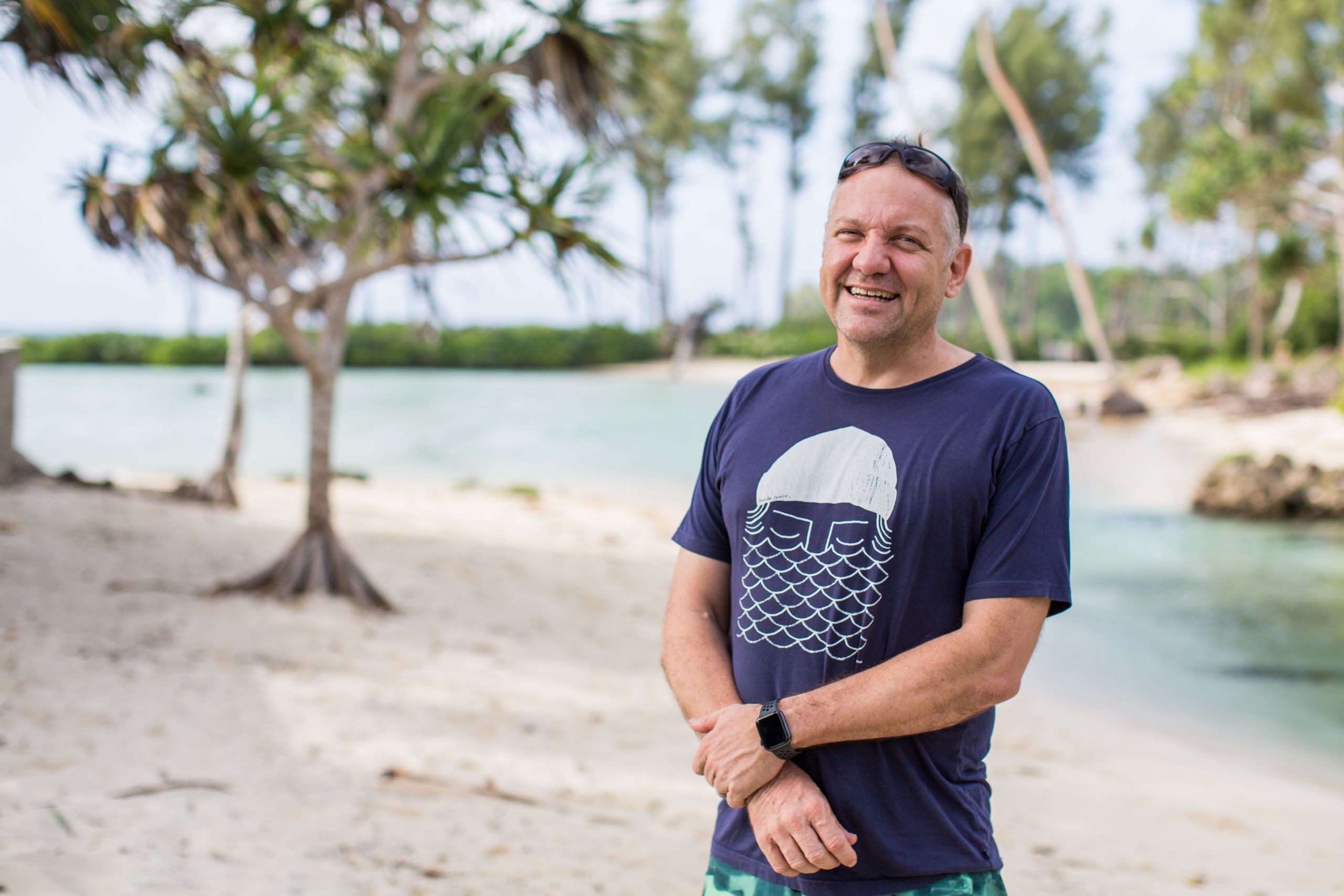 man smiles at camera on tropical beach