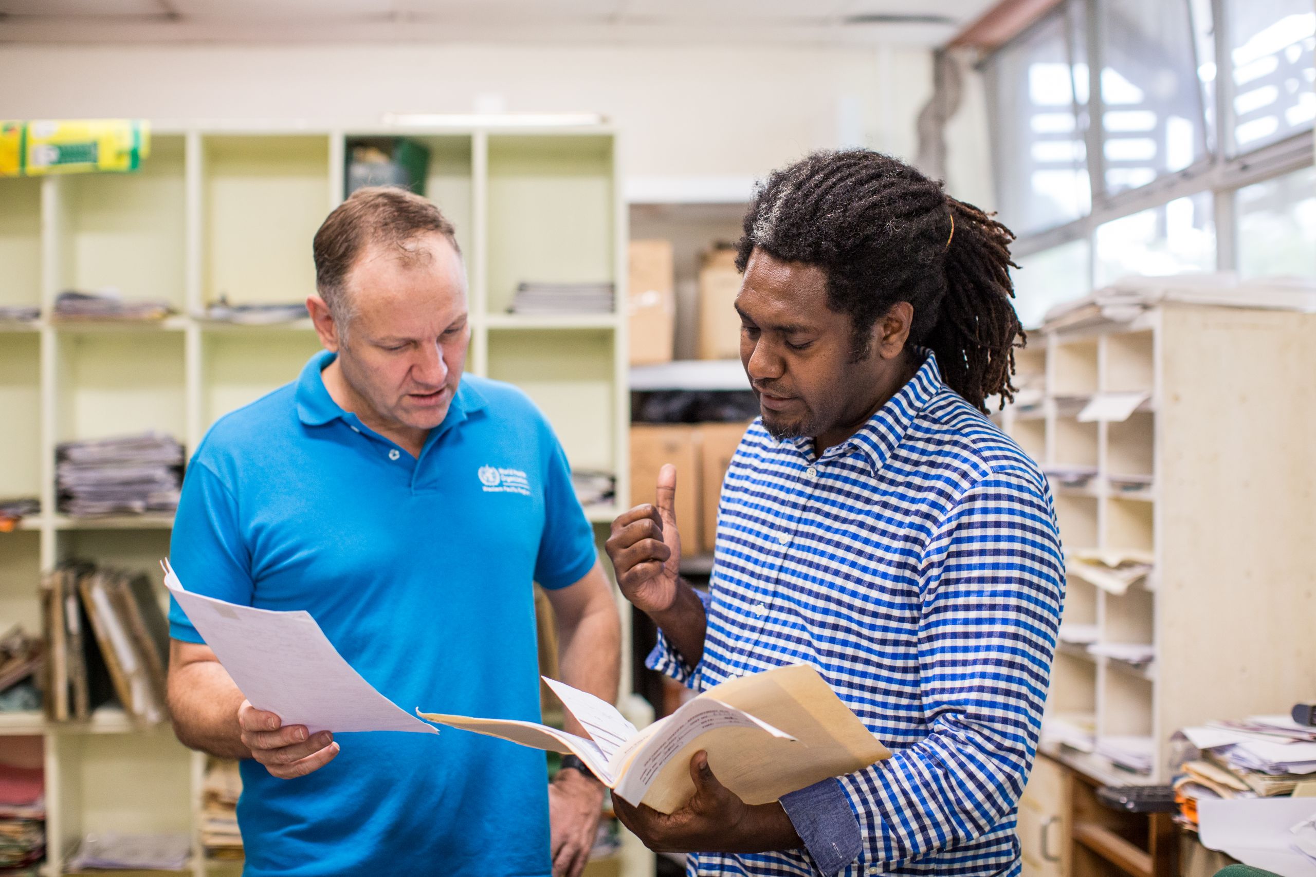 two men holding documents in an office