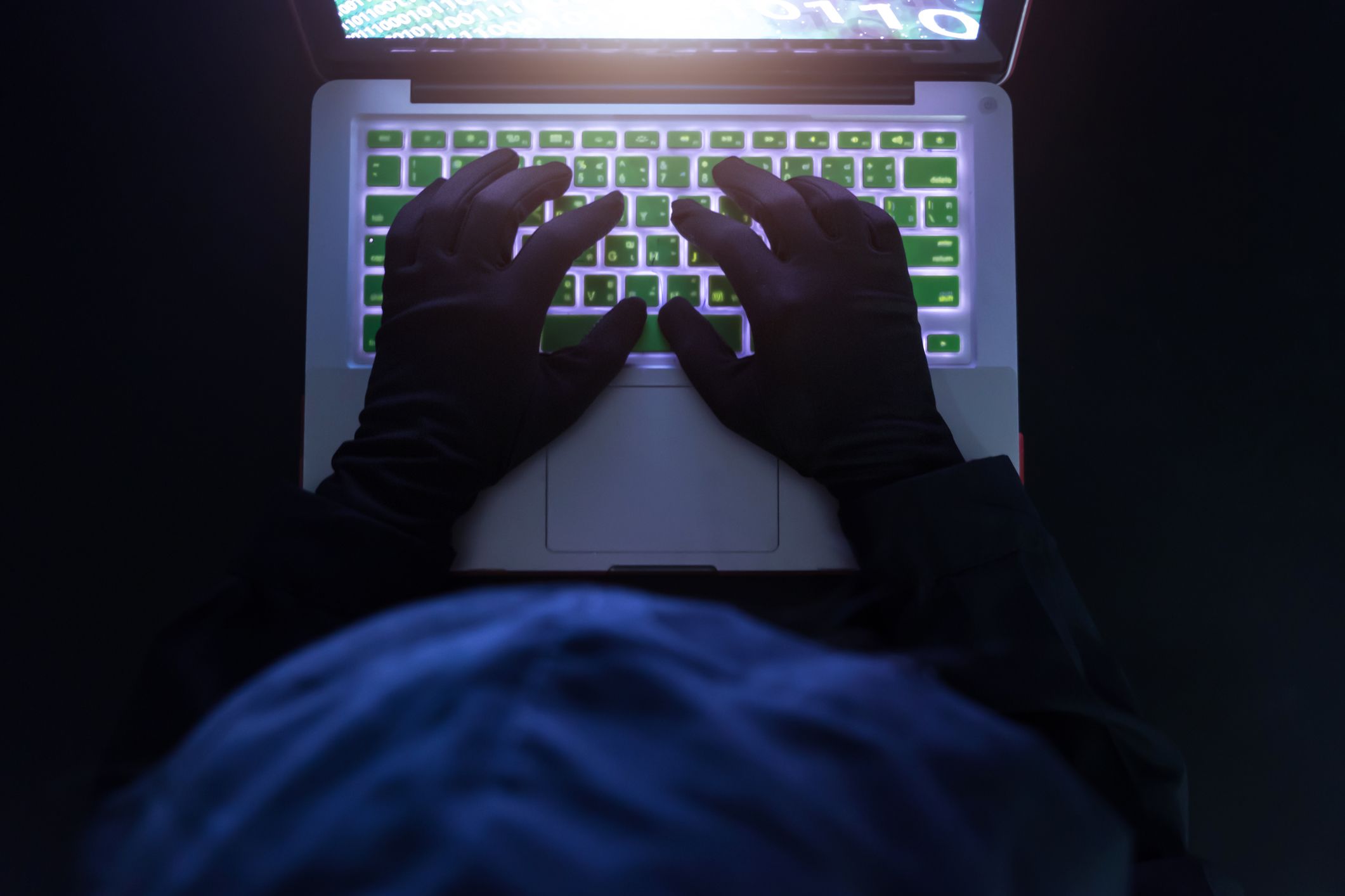 Hands typing on laptop keyboard at night