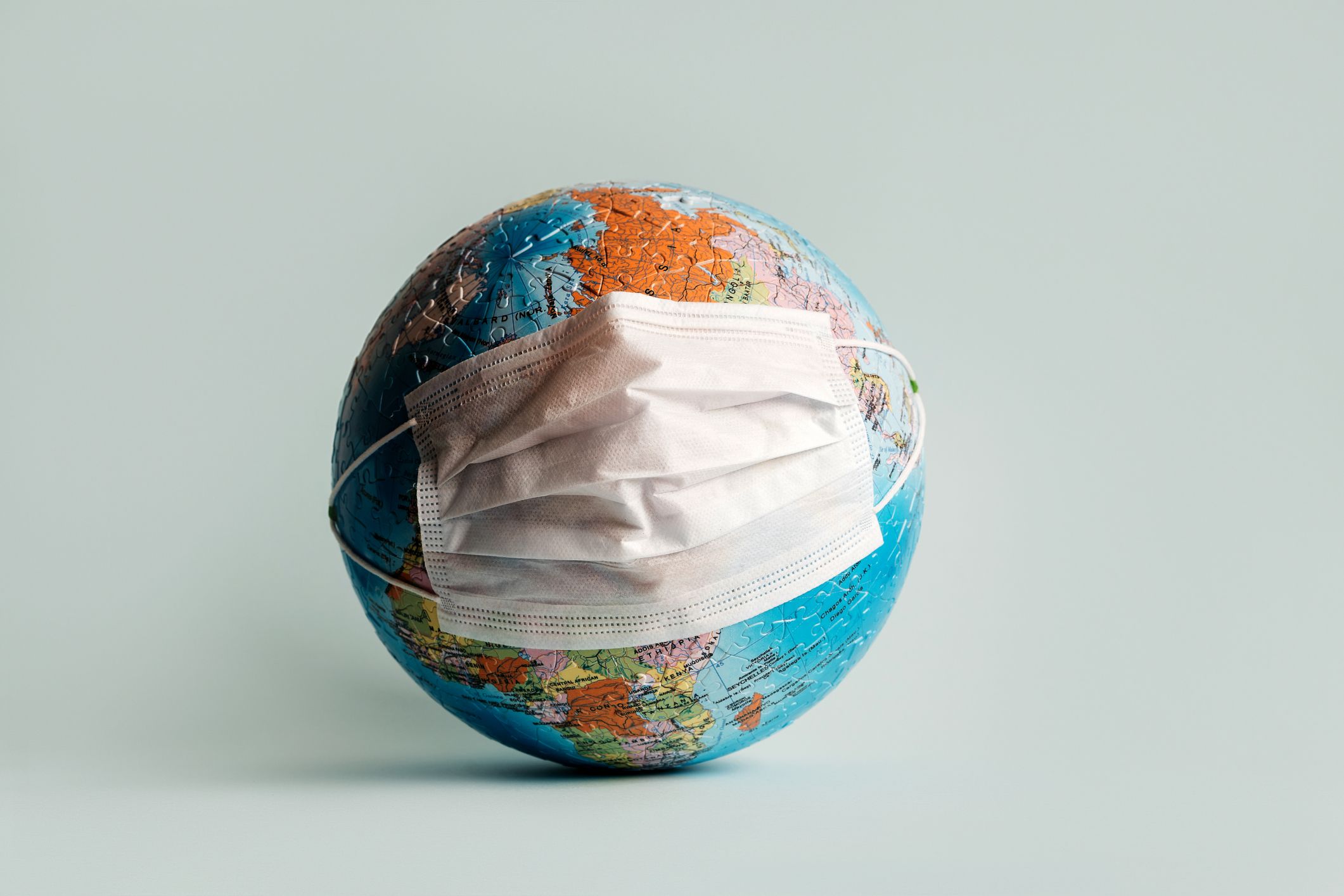 Globe made of Jigsaw Puzzles with protective medical mask.