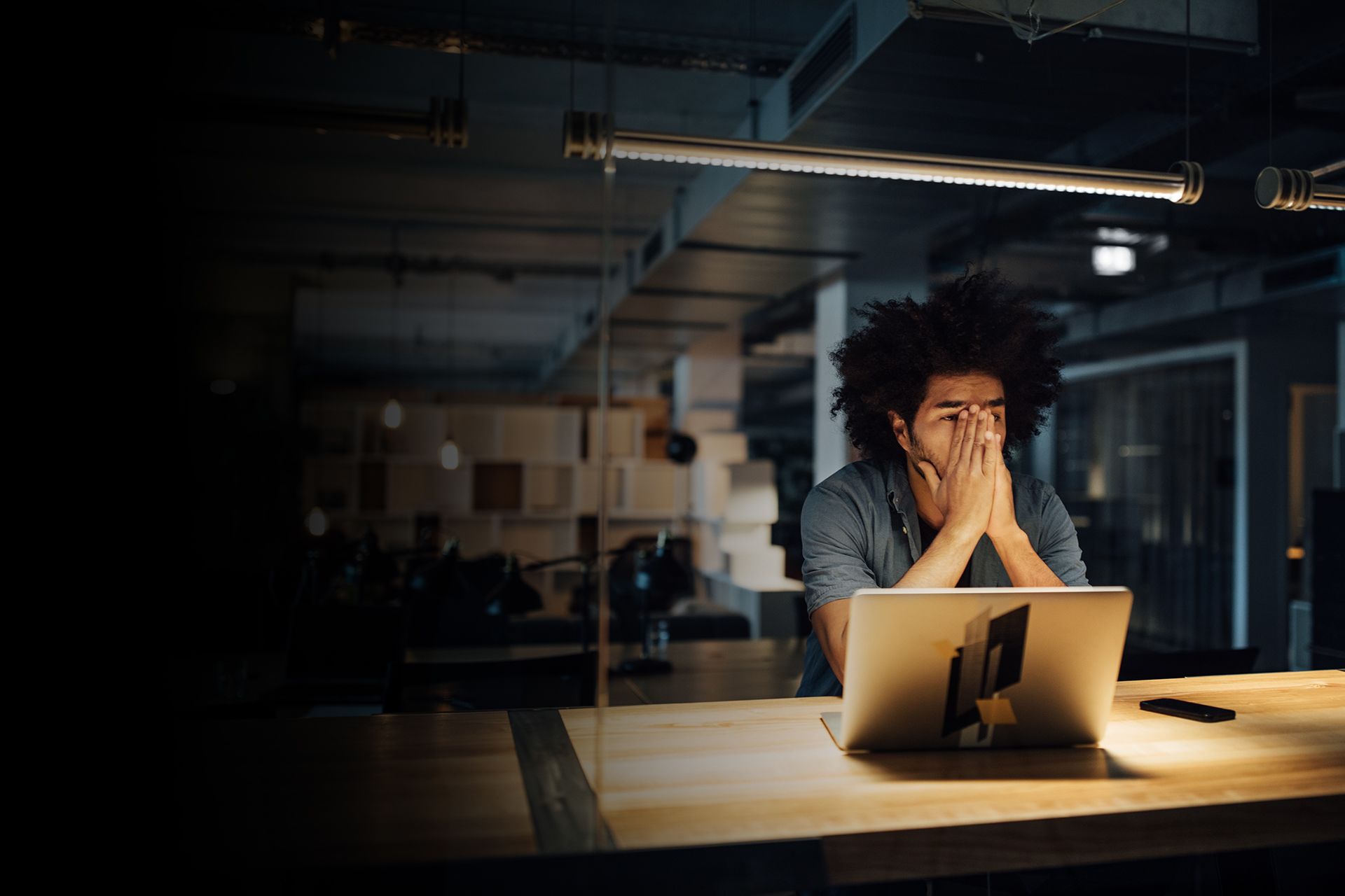 Man sitting at a desk with a laptop experiencing burnout.