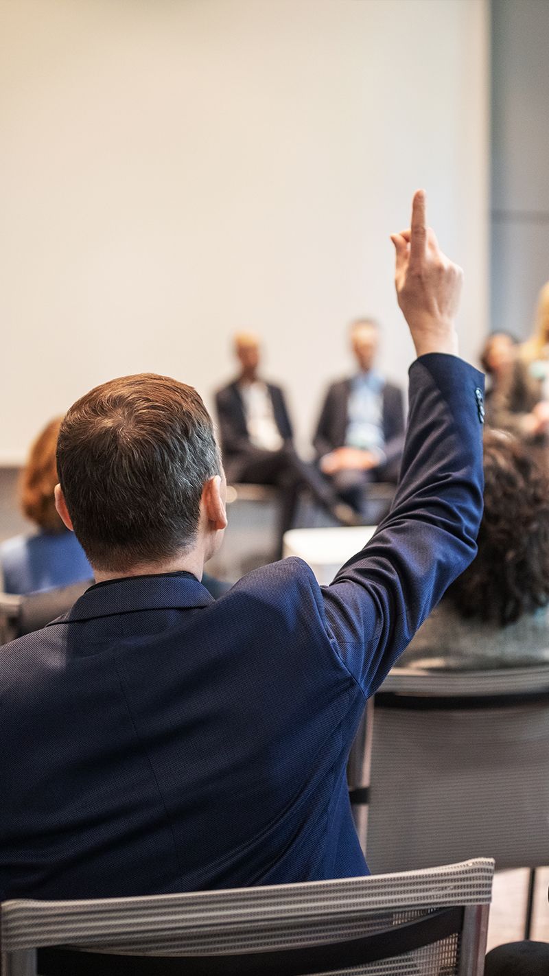 Man raising his hand to ask a question at a conference