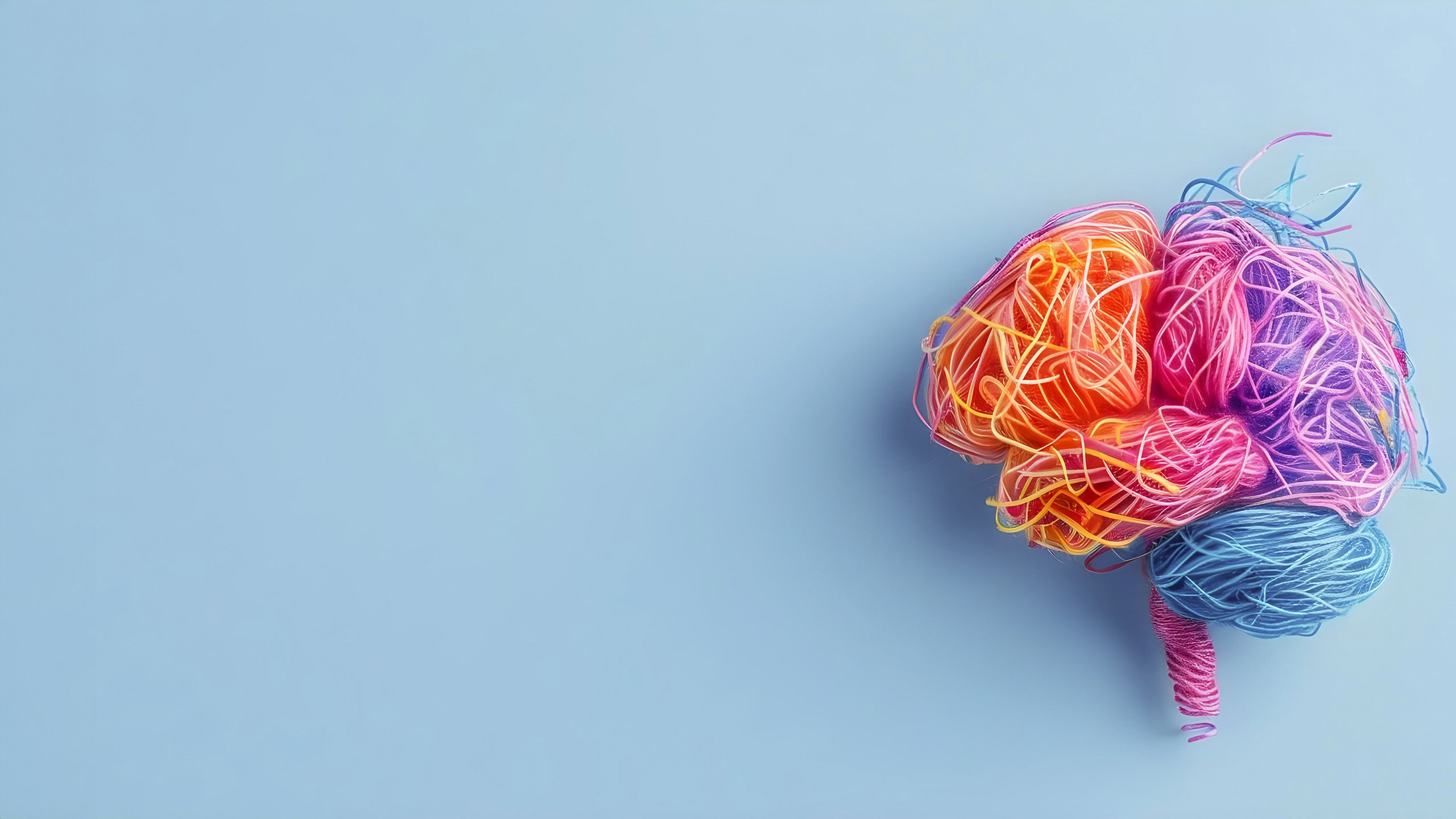 Colourful threads in the shape of a human brain on a light blue background