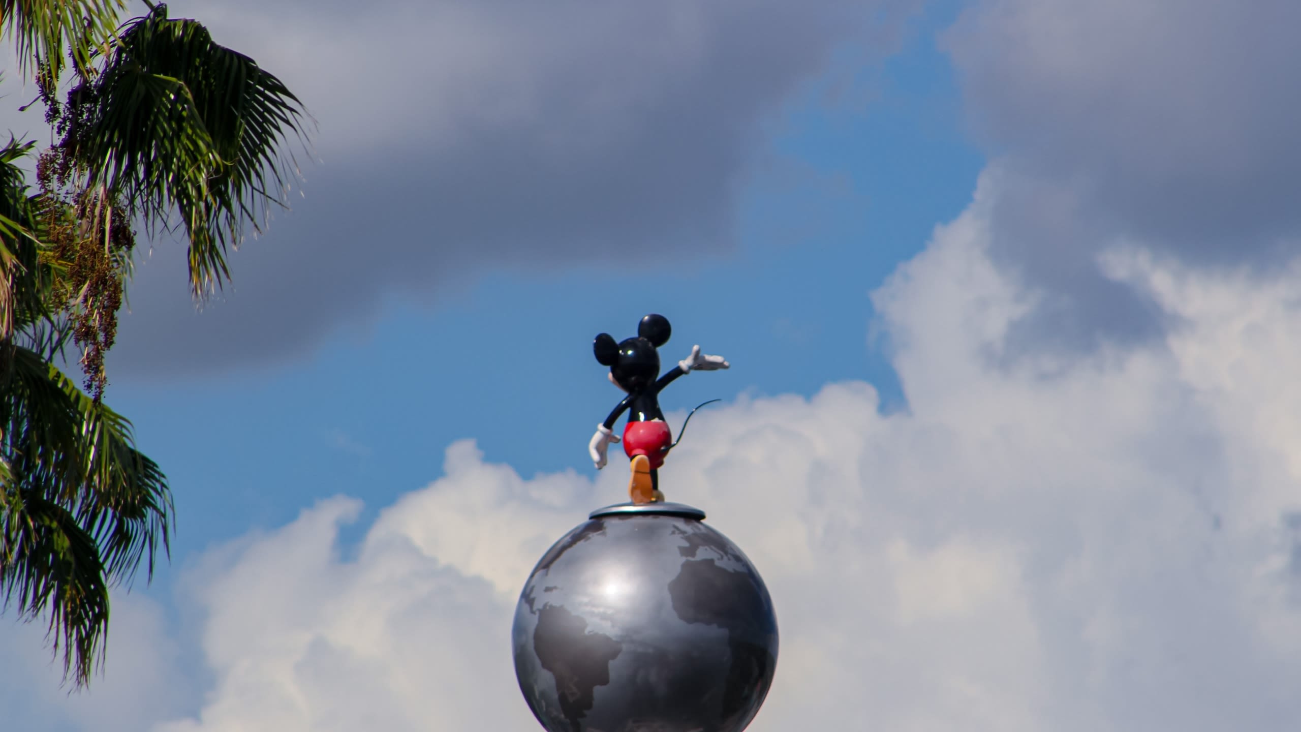 A statue of Mickey Mouse standing on top of a globe
