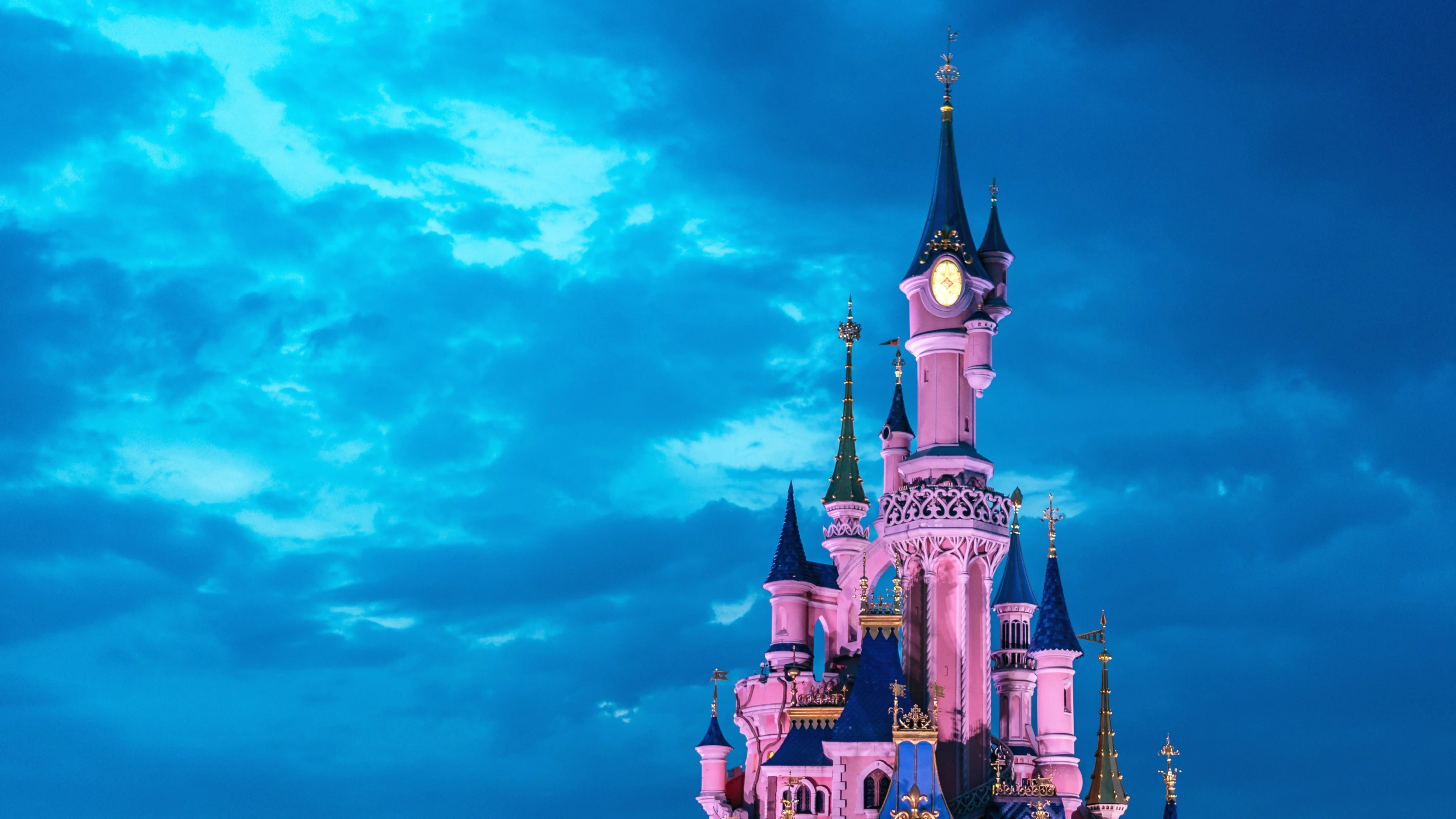 Pink Sleeping Beauty Castle surrounded by blue skies and clouds at Disneyland in Paris in 2019