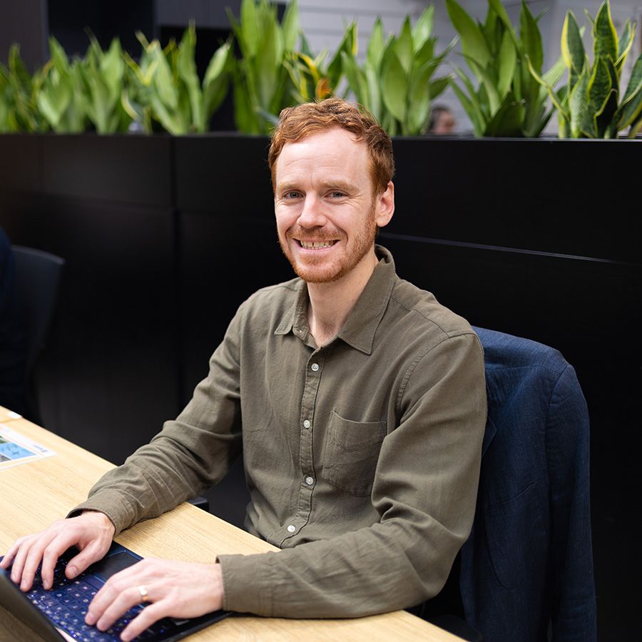 Geoff Smith sitting down with his hands on a laptop in front of plants