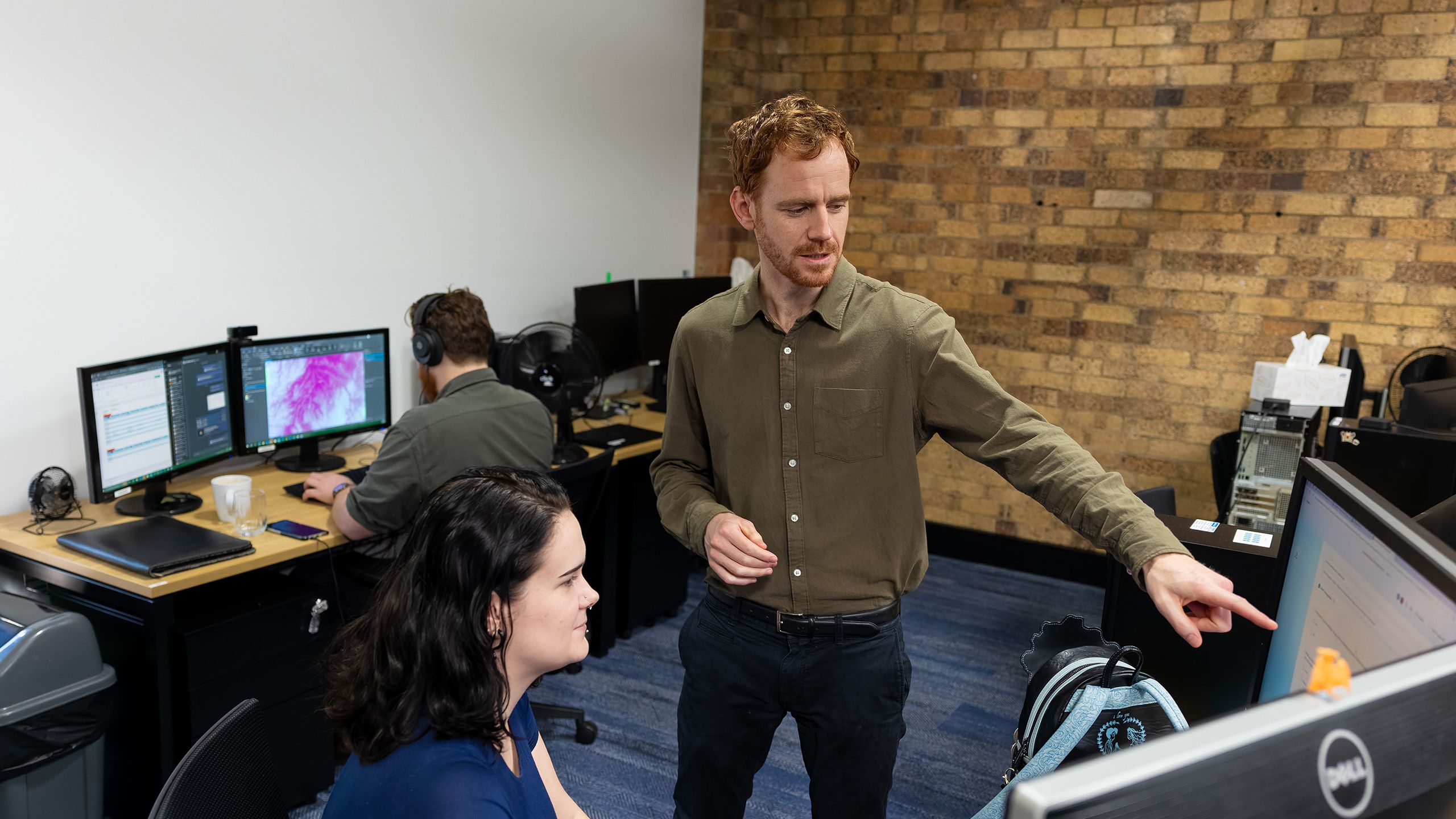 Geoff Smith standing in front of a computer with his hands pointing toward the screen