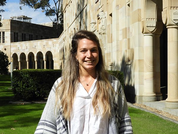 Rosario standing in front of the sandstone in UQ's green Great Court