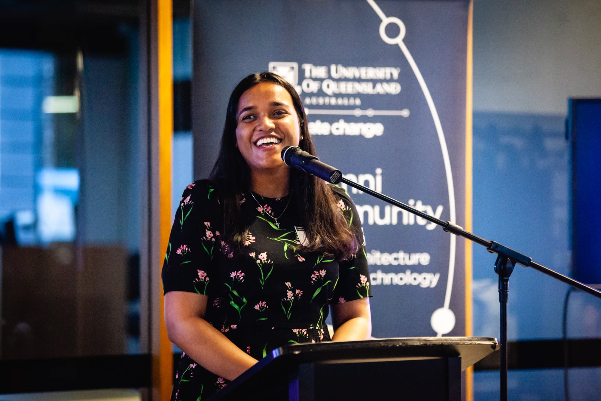 Geethu George speaking at a podium at a Friends of UQ Chemical Engineering event