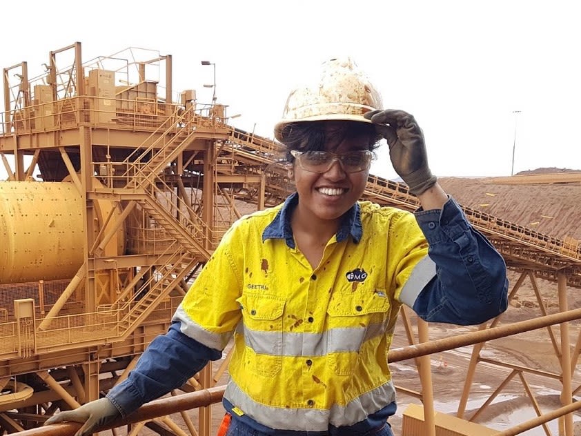 Geethu wearing high vis and a hard hat on site in front of an iron ore platform