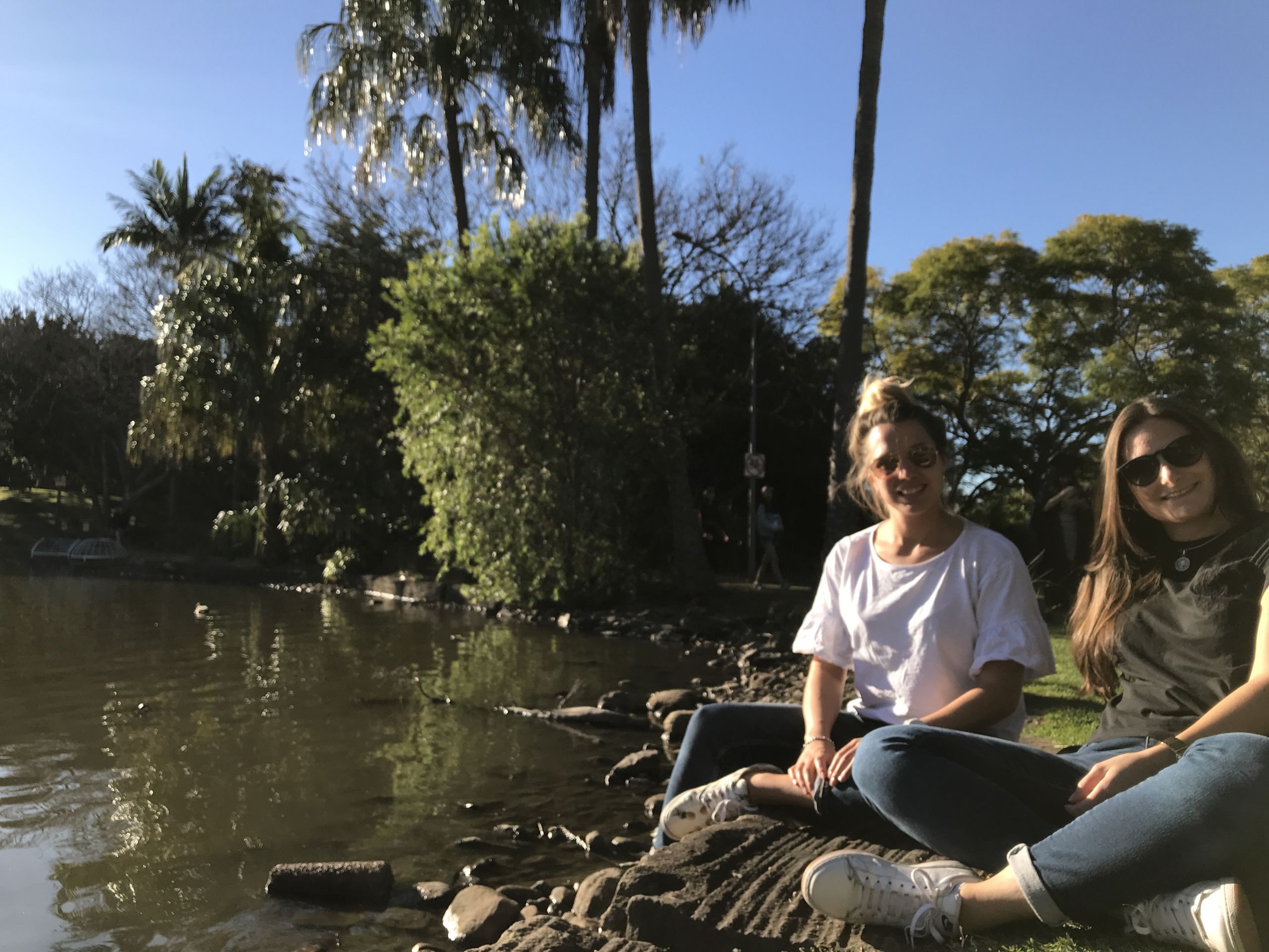 Rosario and a friend sitting on the edge of the UQ Lake