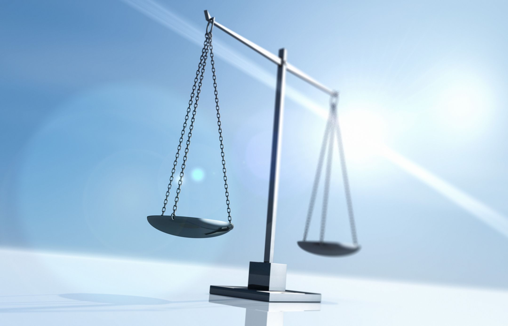 Small set of scales in balance with ray of sunshine behind