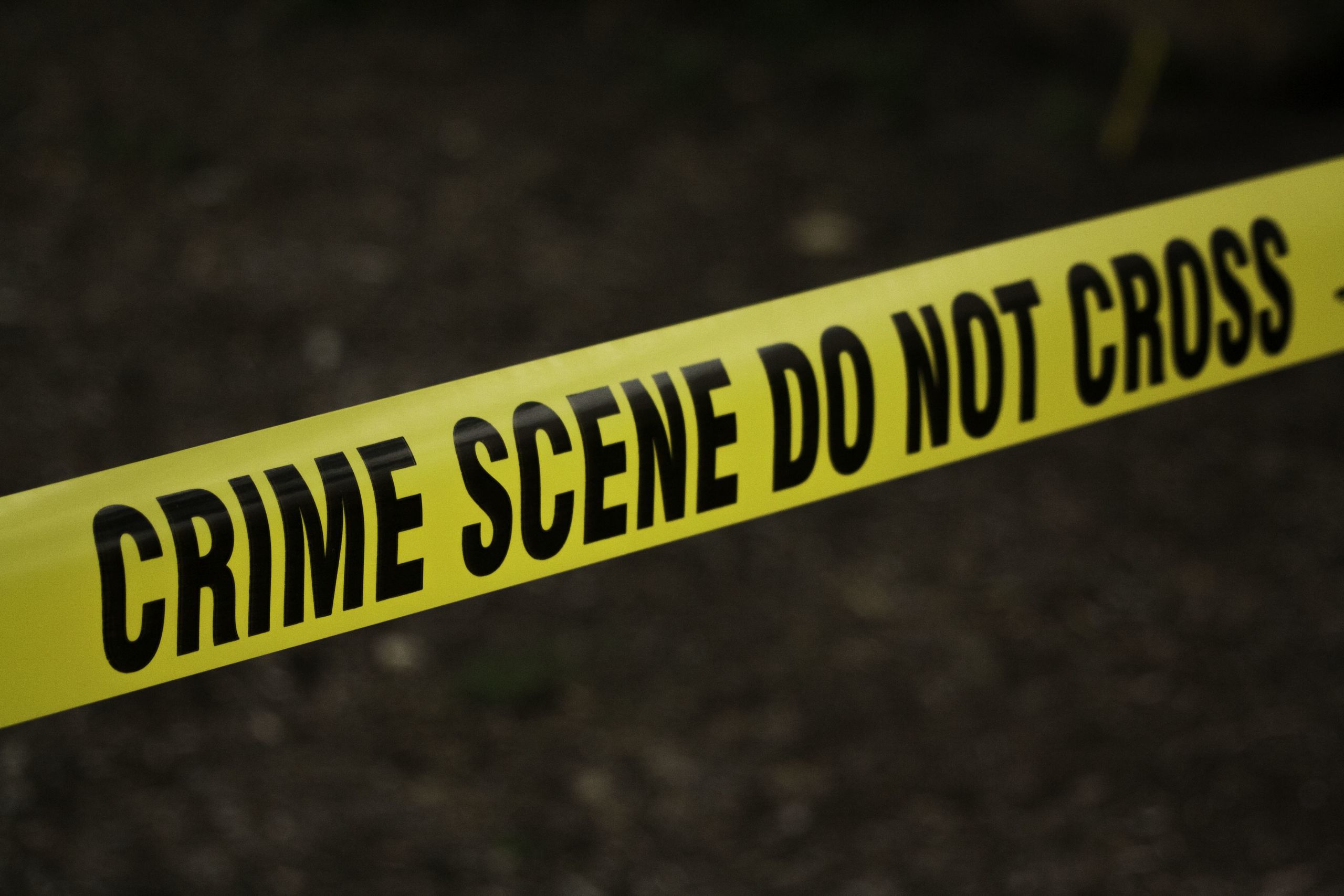 Yellow-coloured crime scene tape saying "crime scene do not cross" pictured diagonally across the screen