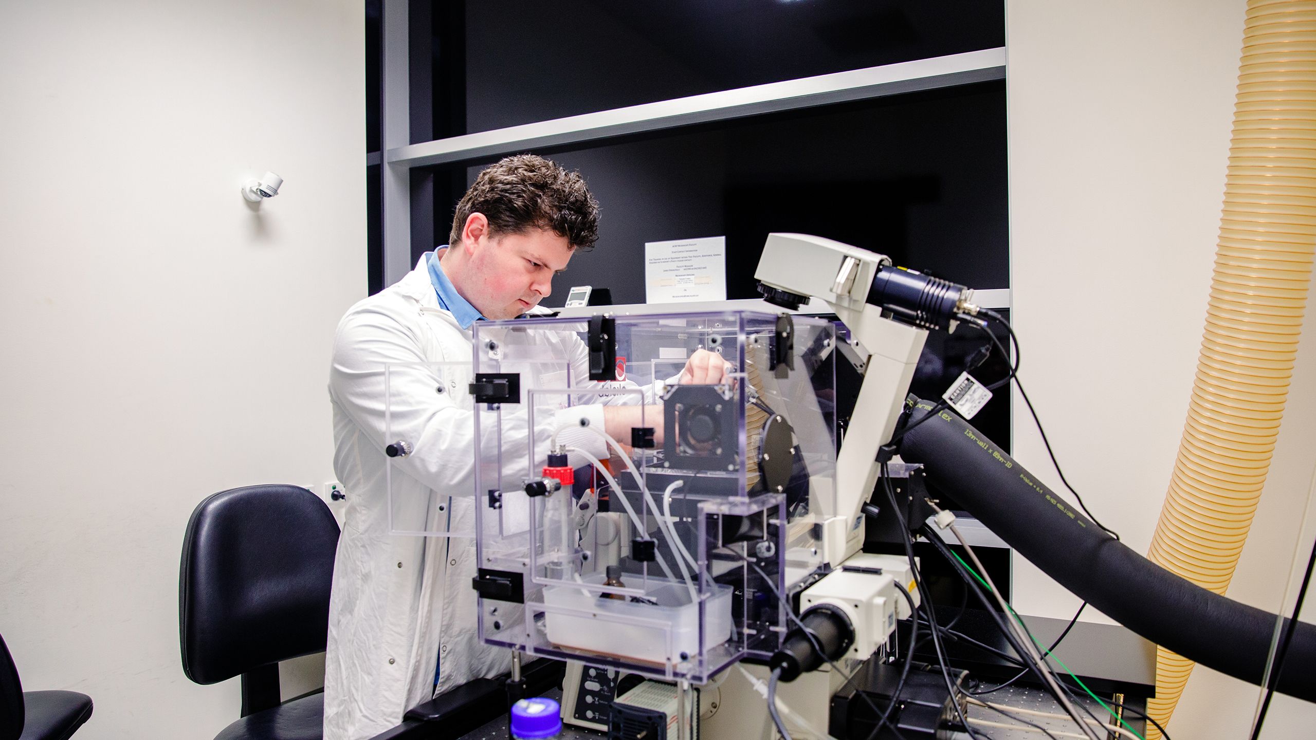 Nicholas Condon working in the ACRF:Cancer Biology Imaging Facility, setting up an experiment on a Nikon automated widefield microscope.