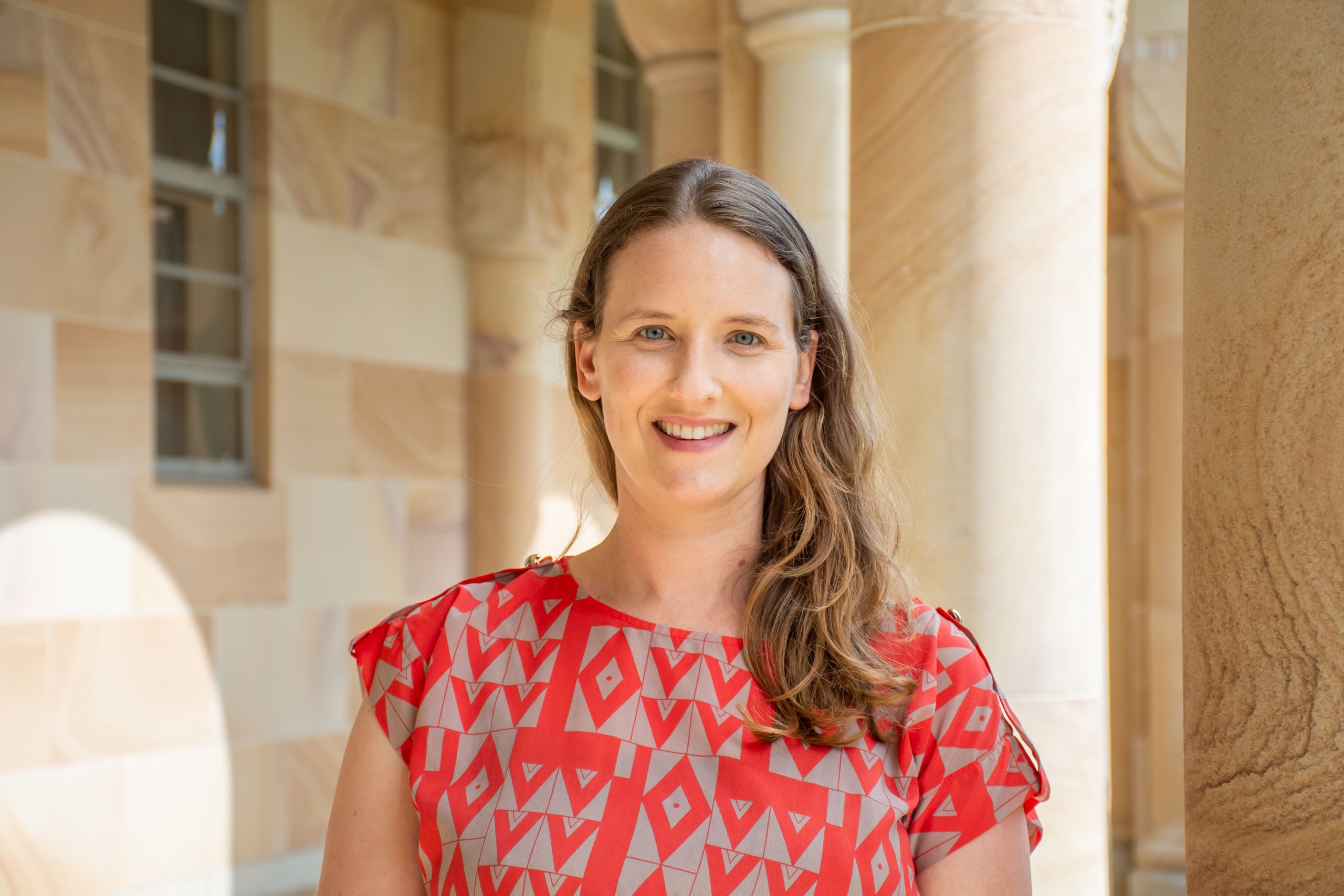 UQ Ridge to Reef Fisheries Team member Dr Amelia Wenger standing in front of UQ's sandstone.