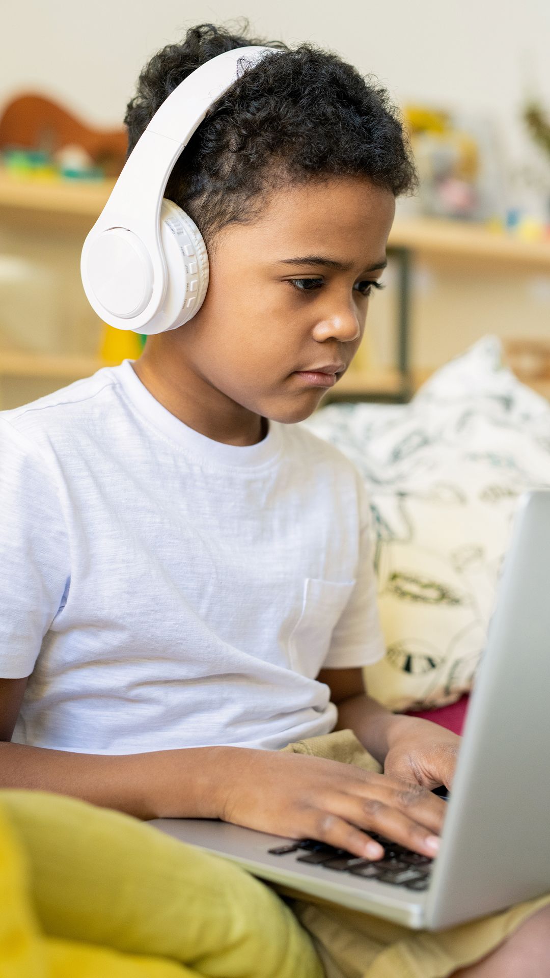 Young child with headphones on playing on the computer.