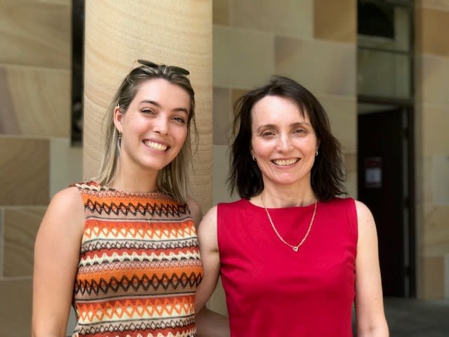 Daughter and mother with arms around each other in front of UQ sandstone
