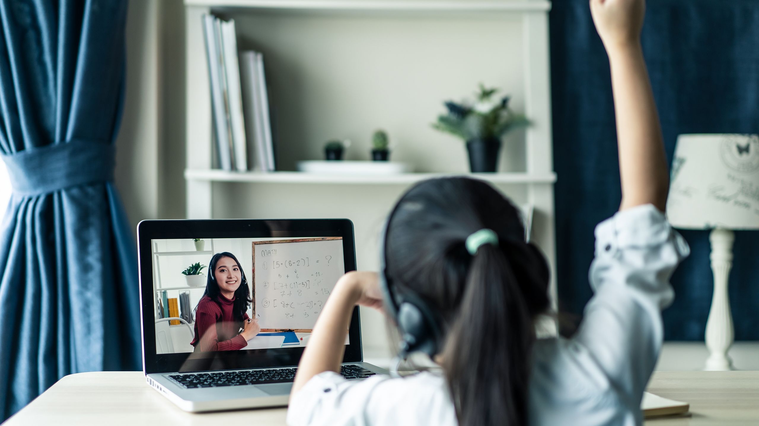 Young child facing computer screen with teacher providing home-school lesson.