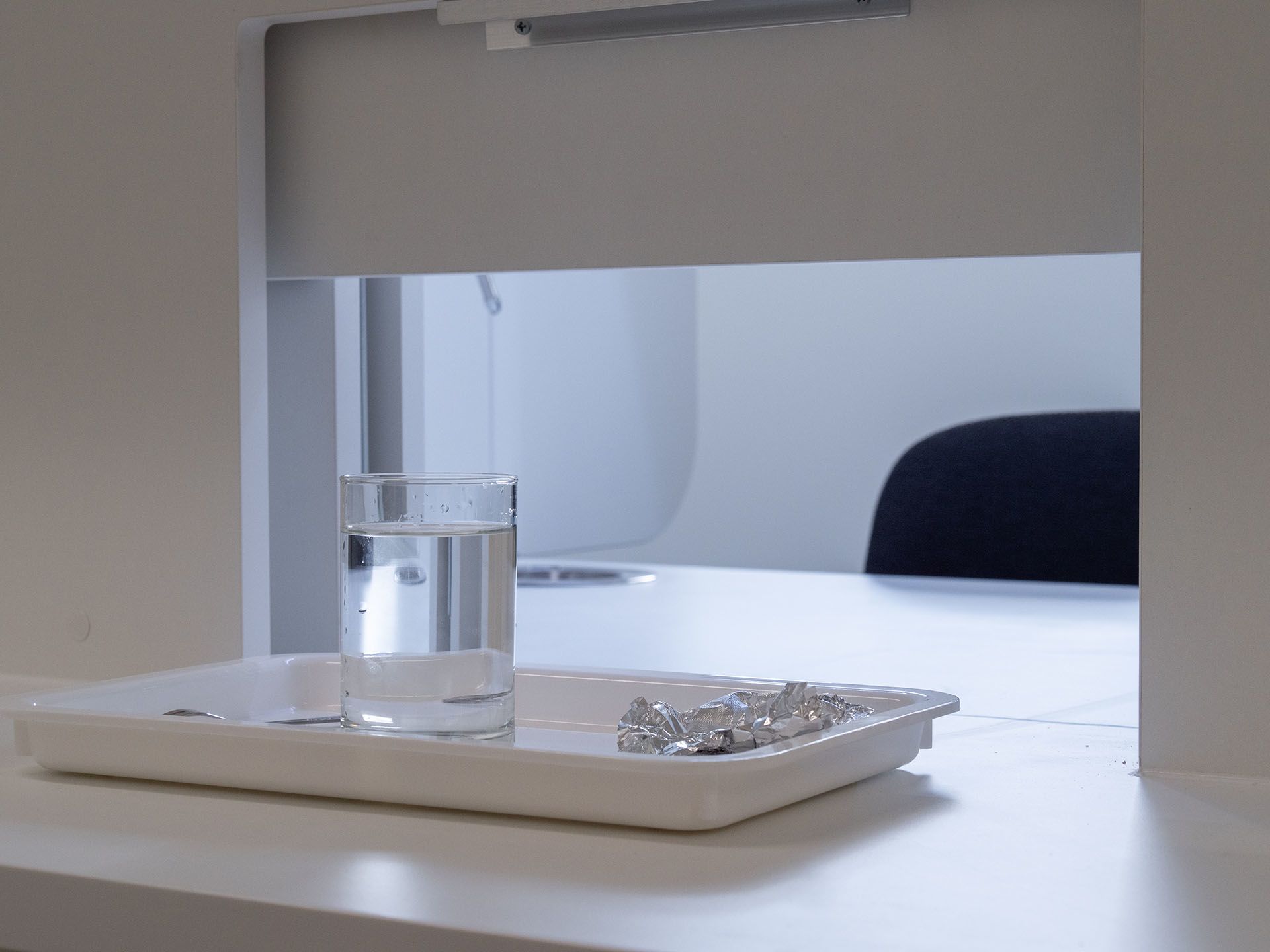 Sample on a plate with a glass of water, about to be pushed through a window for a taster to sample