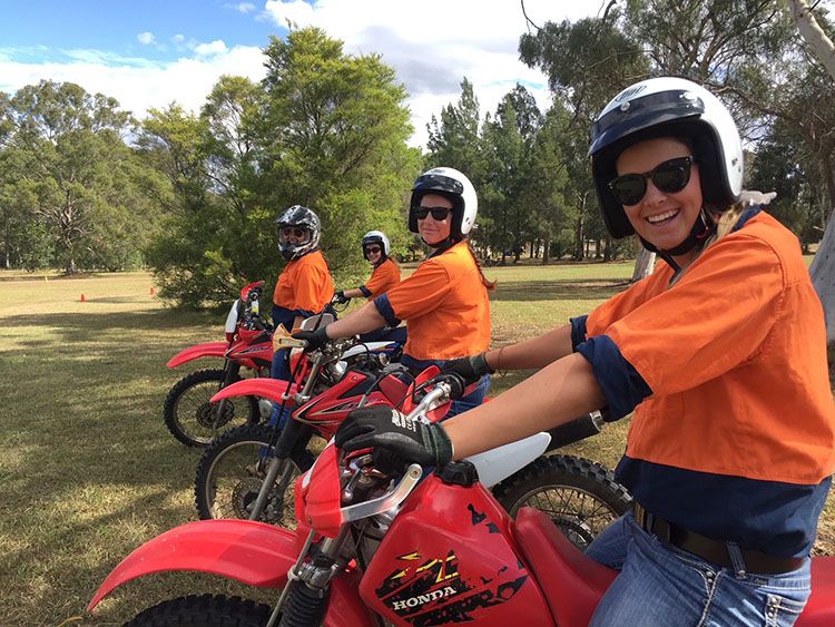 Four students in orange high vis shirts riding motor bikes