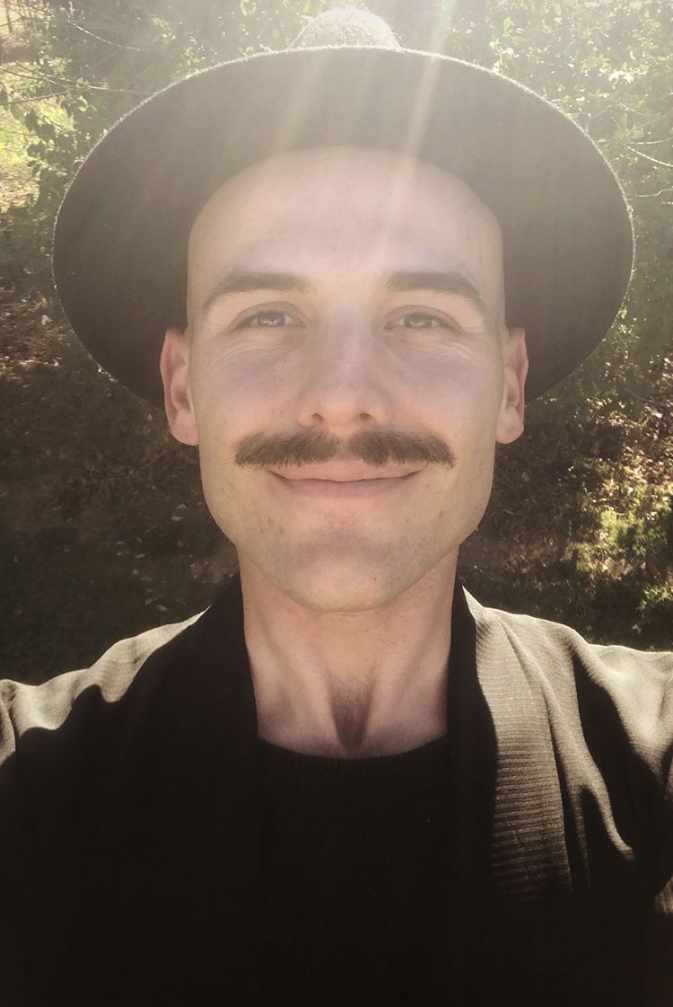 A selfie of a man with a dark moustache wearing a black hat