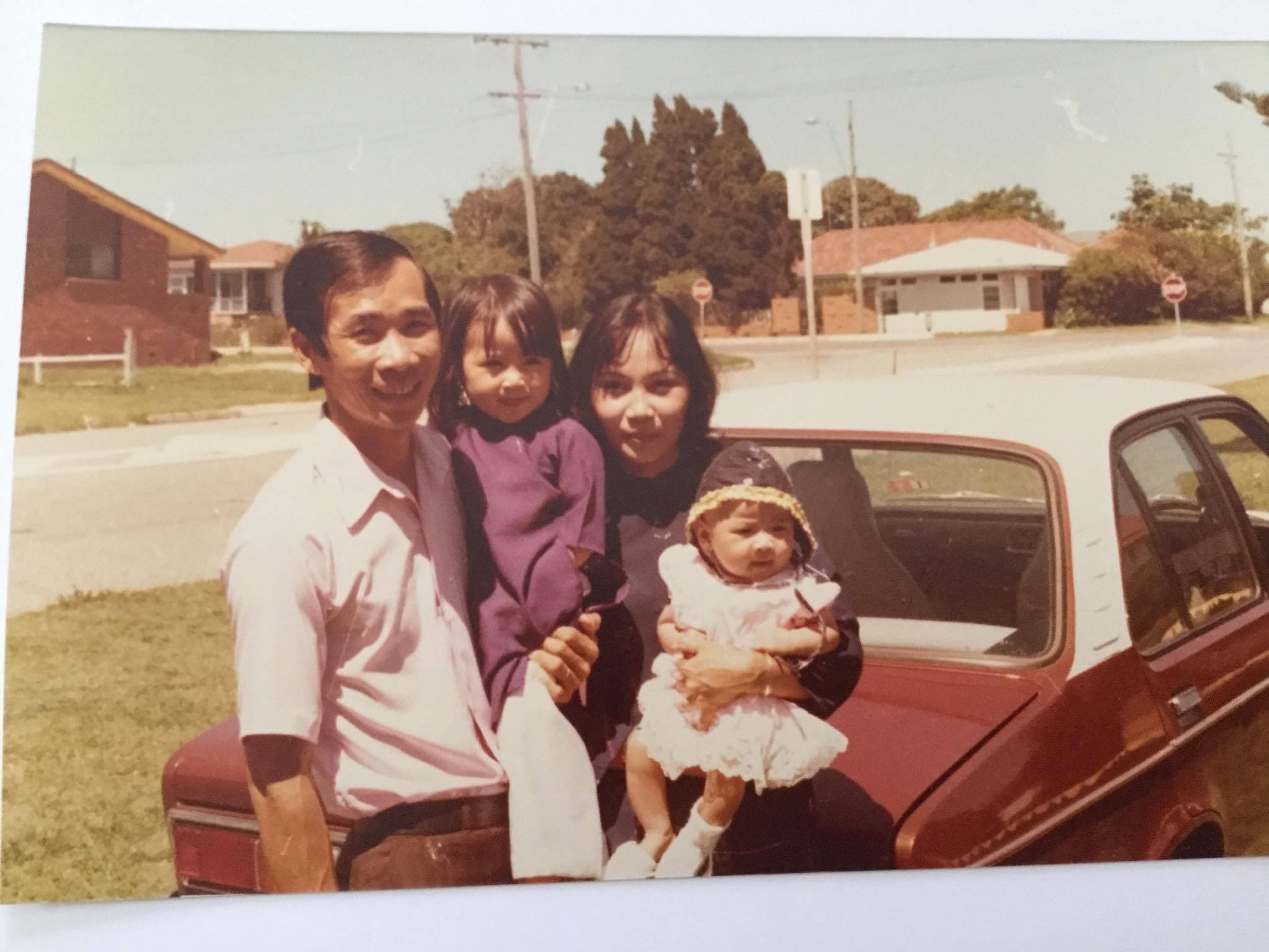 A vintage photo of a father and mother holding their two small children and smiling towards the camera.