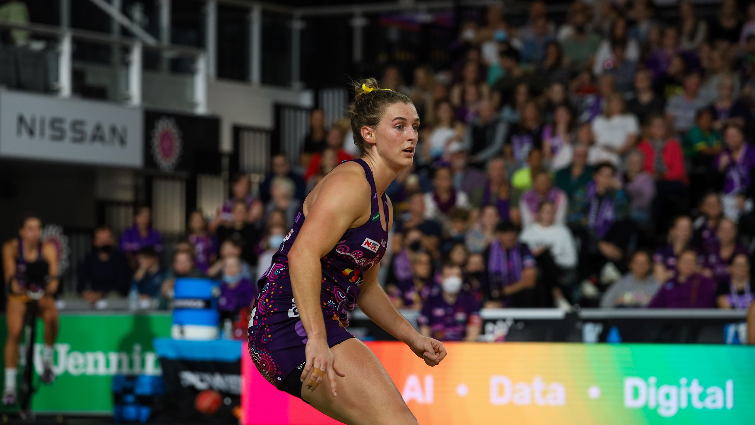 Gabi Simpson wearing a purple Firebirds netball dress moving on the court