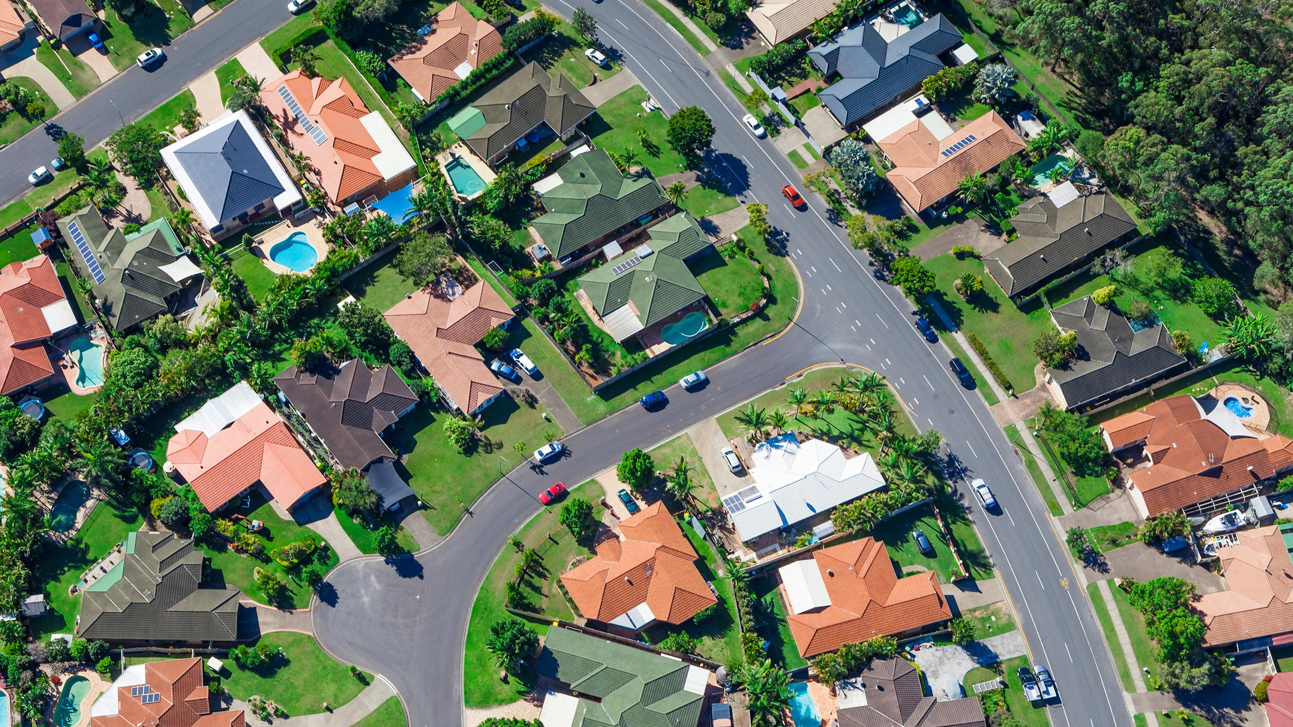 An aerial view of an Australian suburb with houses, trees and two streets