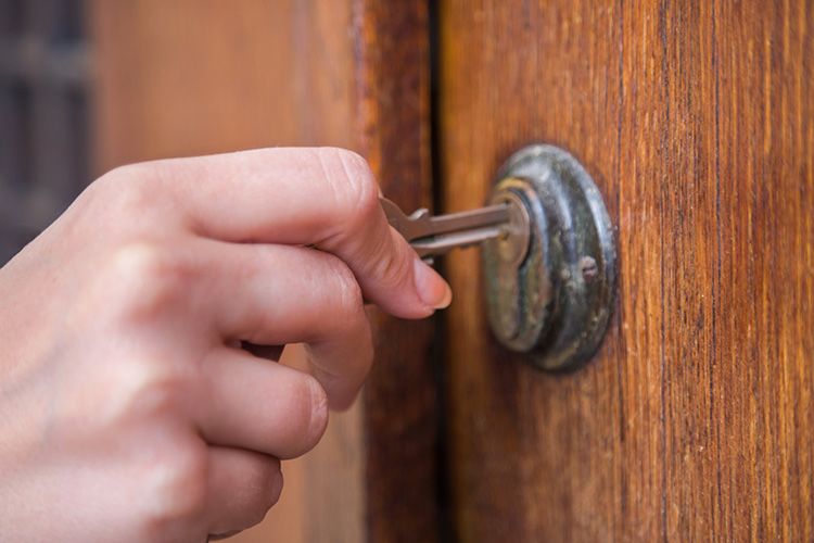 A hand placing a key into door lock