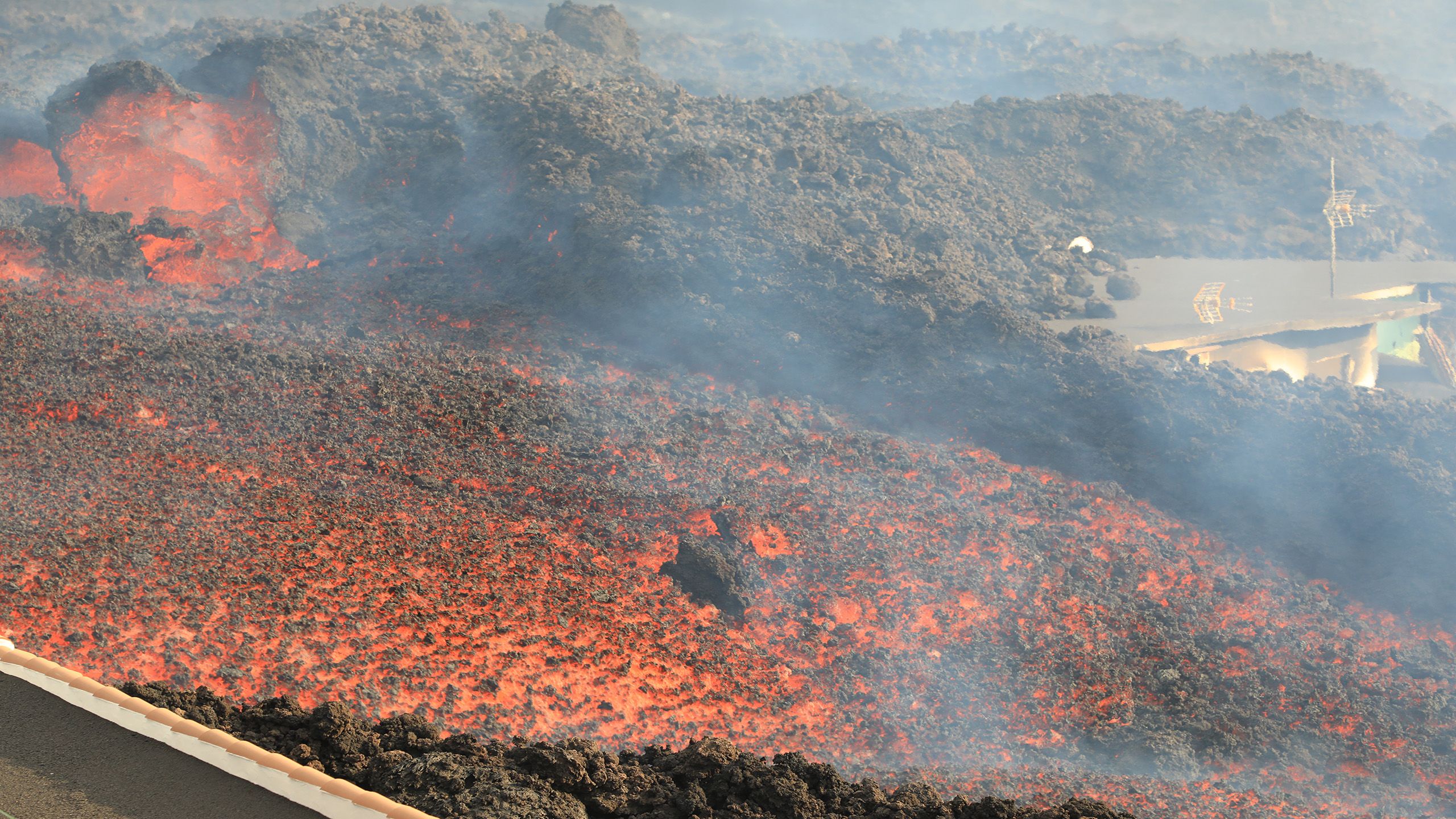 Rocky, bright orange magma with smoke billowing on the surface